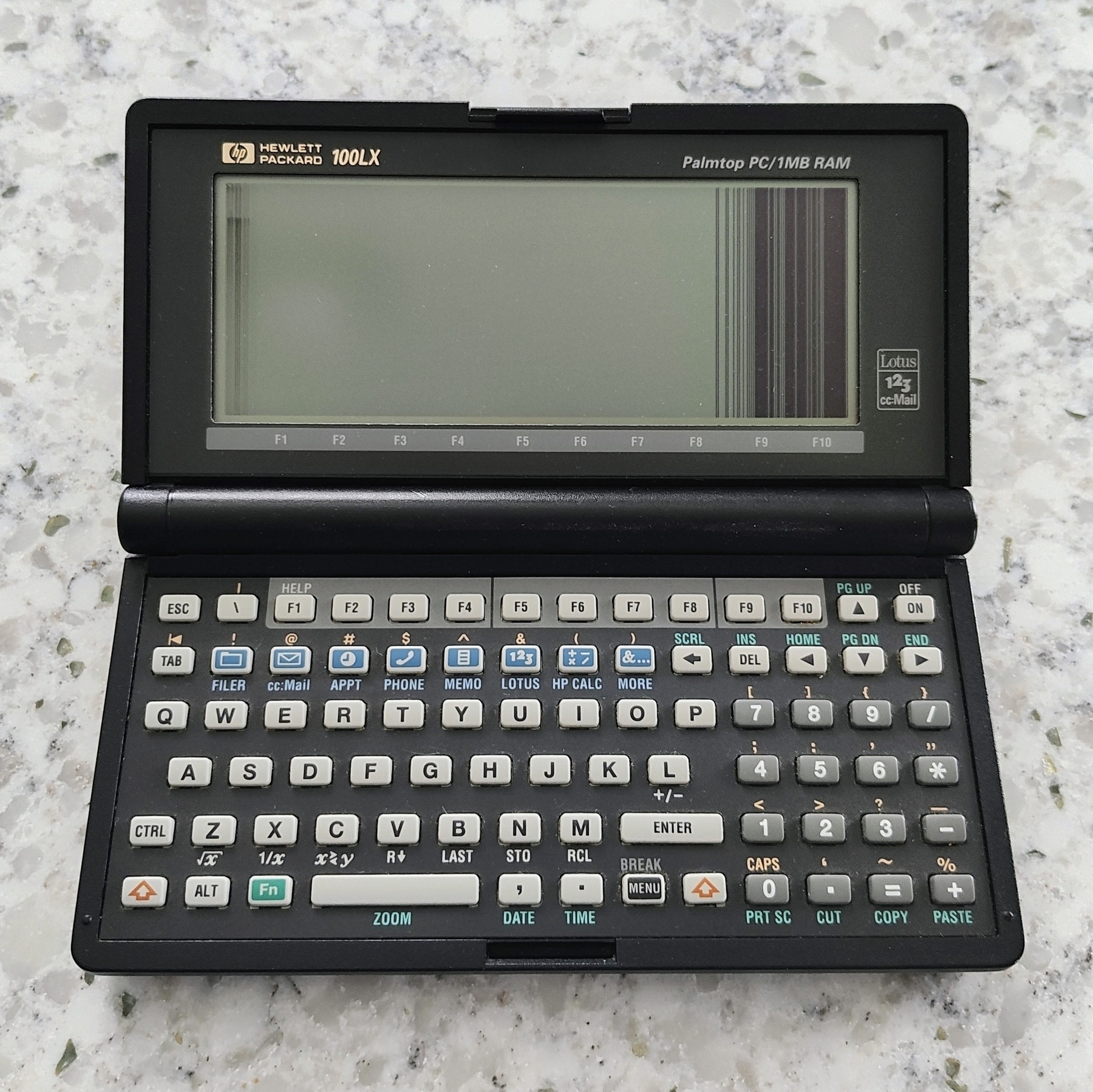 An HP 100LX palm top computer showing scrambled lines on its monochrome LCD screen