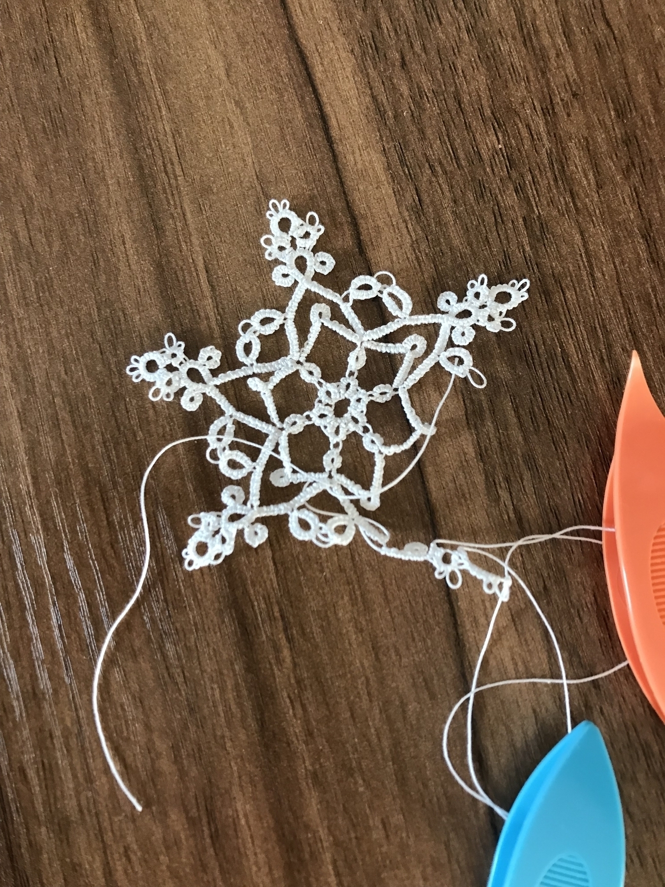 half-finished tatted white snowflake on a desk, with the shuttles still attached”></p>

        </div>
      </li>
    
      <li class=