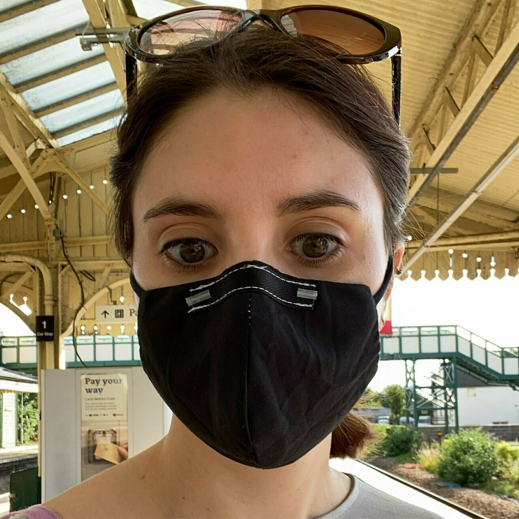 Me, wearing a black fabric mask at a train station