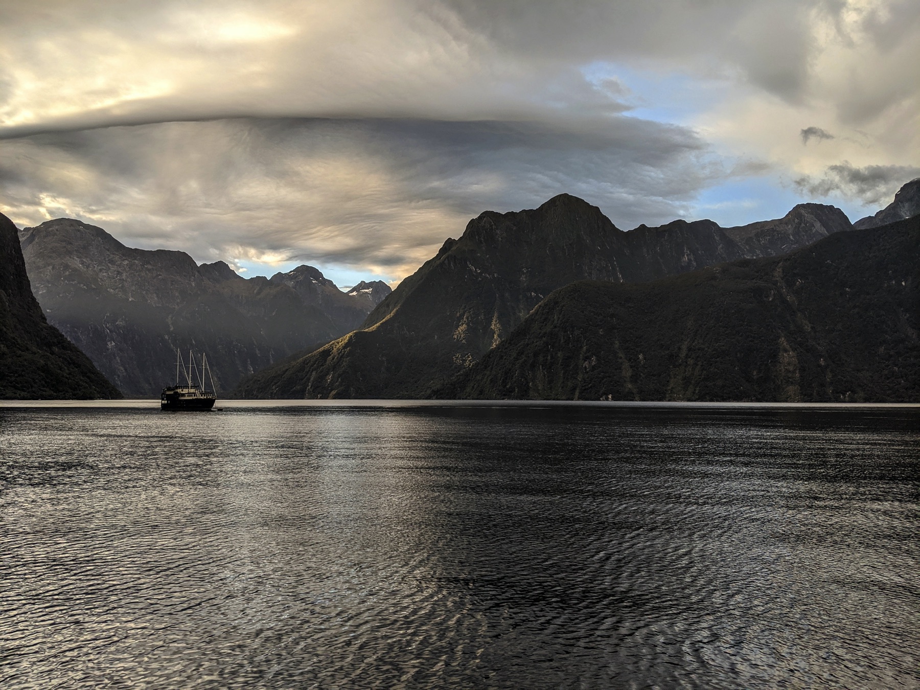 Image a boat at sunrise on Piopiotahi (Milford Sound) in New Zealand’s South Island.