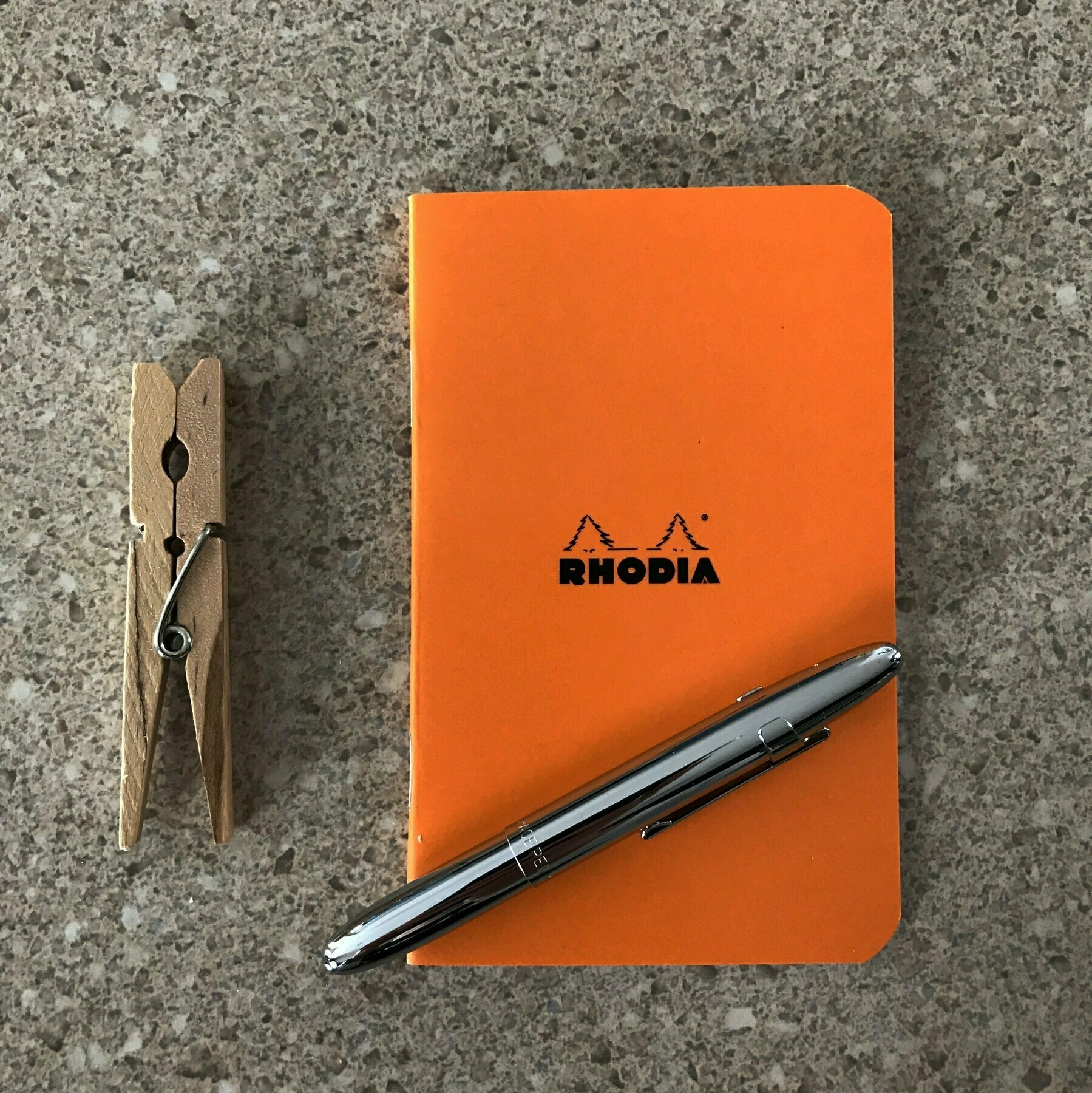 orange pocket notebook with silver pen