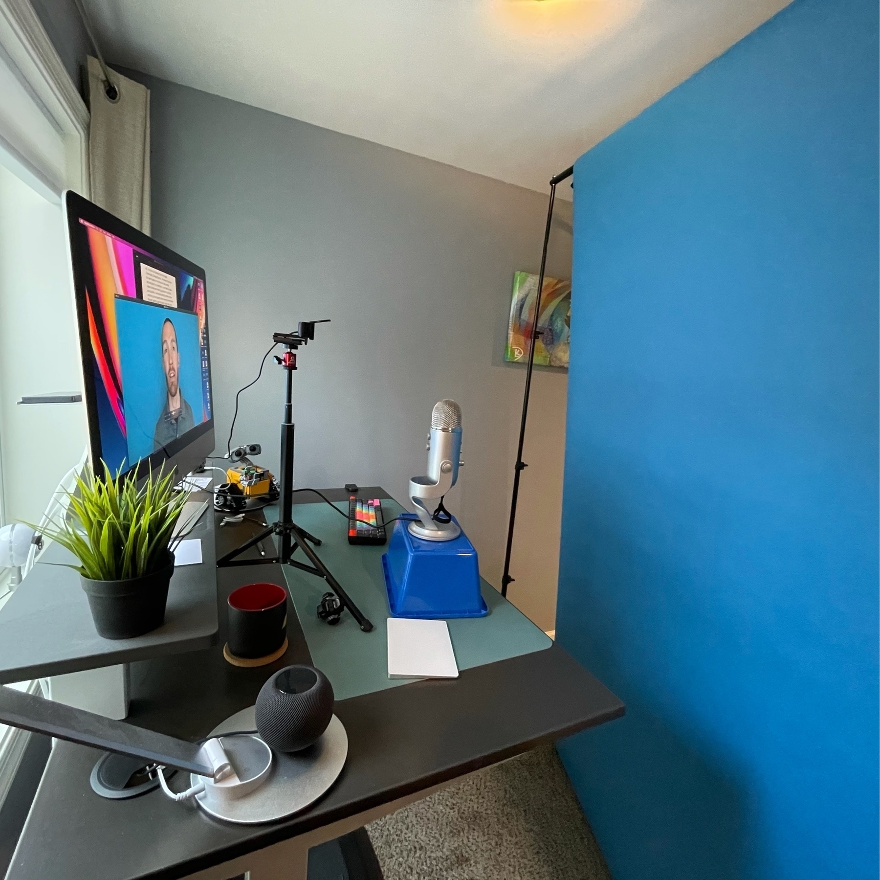 desk set up with computer, webcam, microphone, and blue screen in front of it