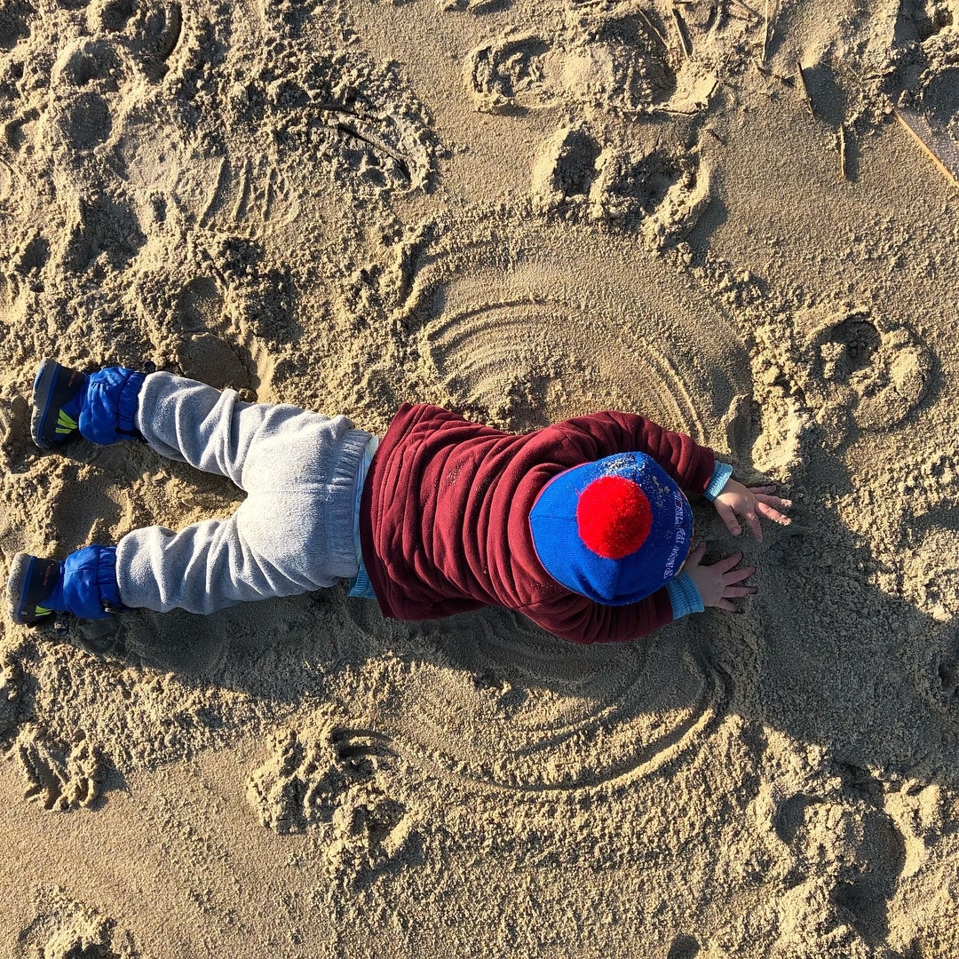 boy laying in the sand 