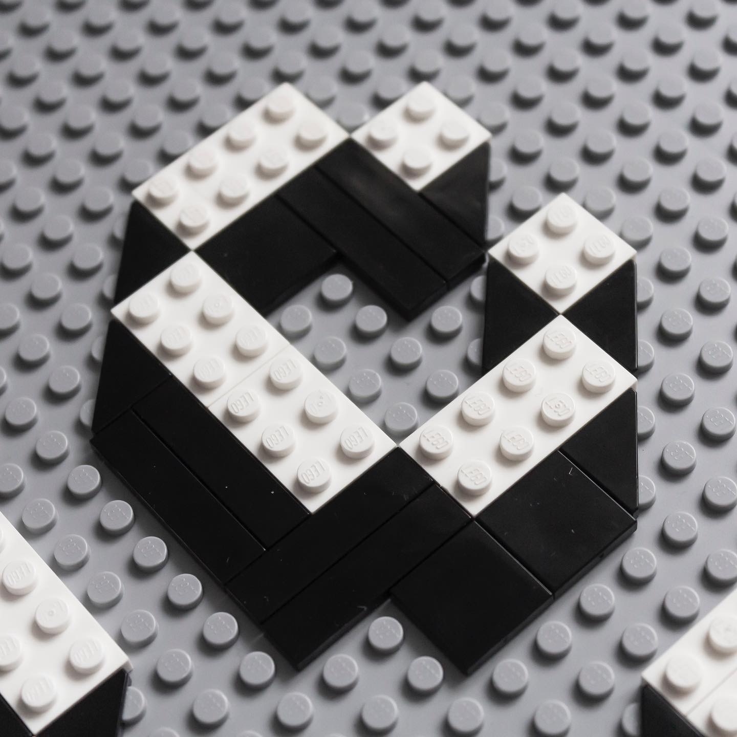 White letter C on a grey background, drawn with Lego blocks.