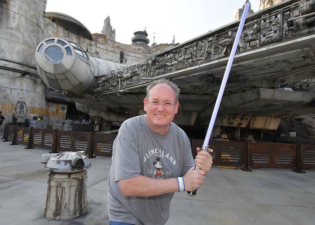 James with lightsaber in front of Millenium Falcon at Star Wars: Galaxy’s Edge at Disneyland.