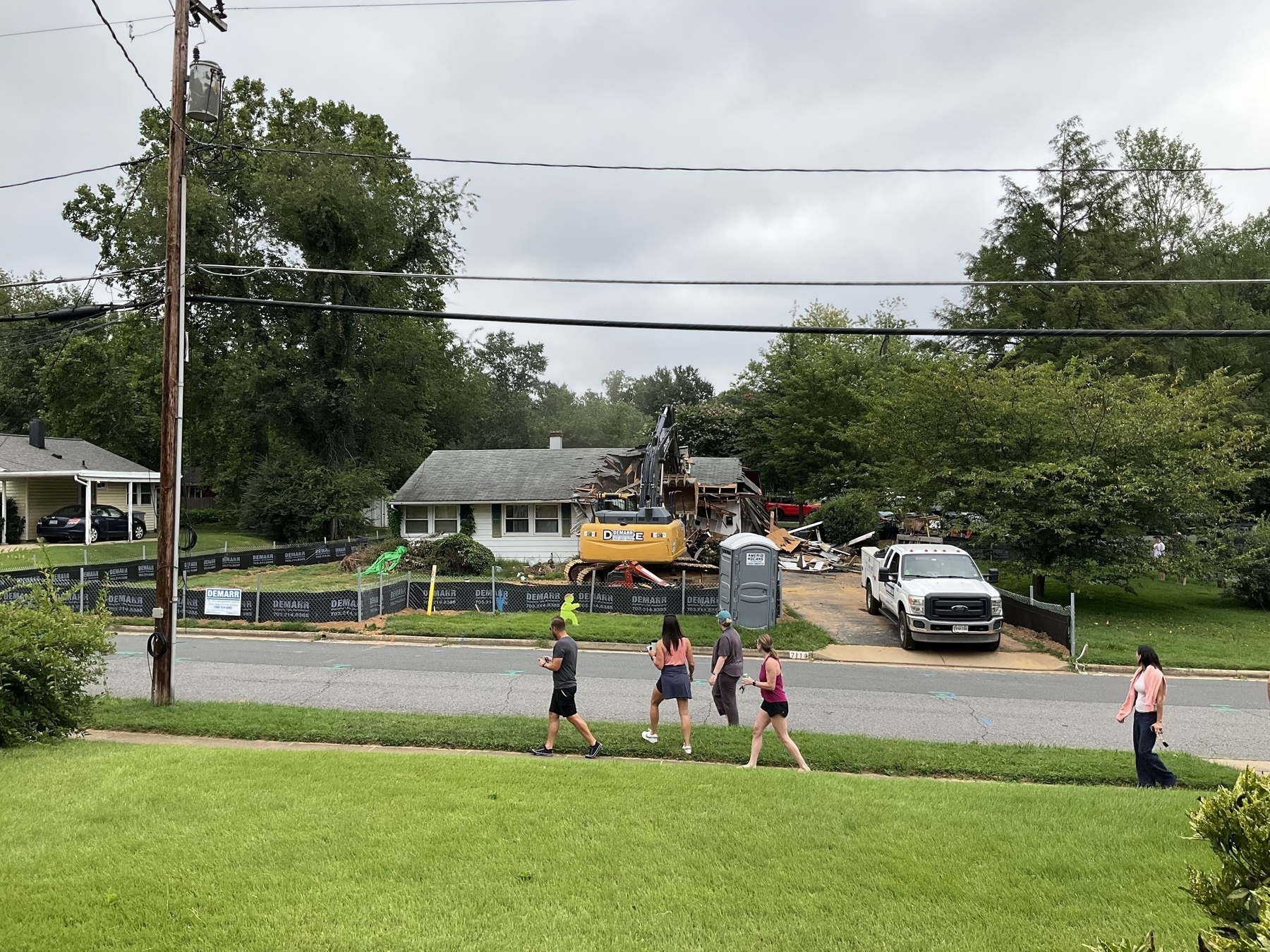 A suburban house is being demolished. Spectators are gathering. 