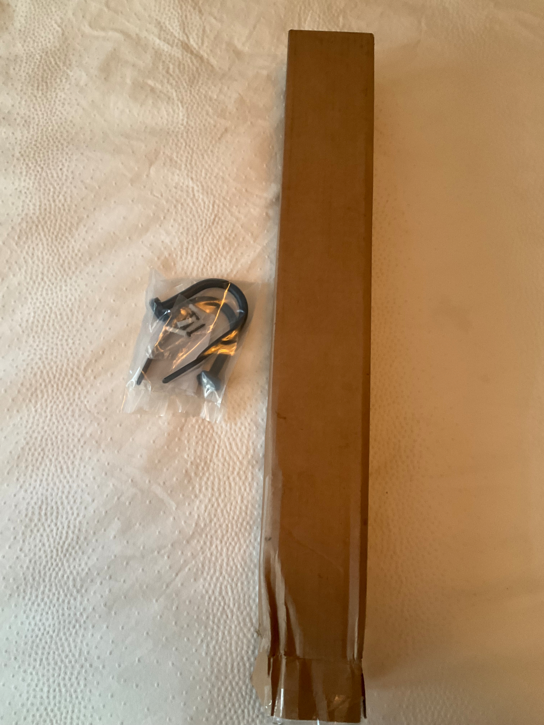 A couple of curtain hooks, maybe five inches long, are sitting next to the box they were delivered in, which is about 30 inches long. 