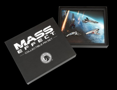 Auto-generated description: A boxed set labeled Mass Effect Collectible Pin Set contains pins shaped like various spacecraft from the Mass Effect series against a space background.