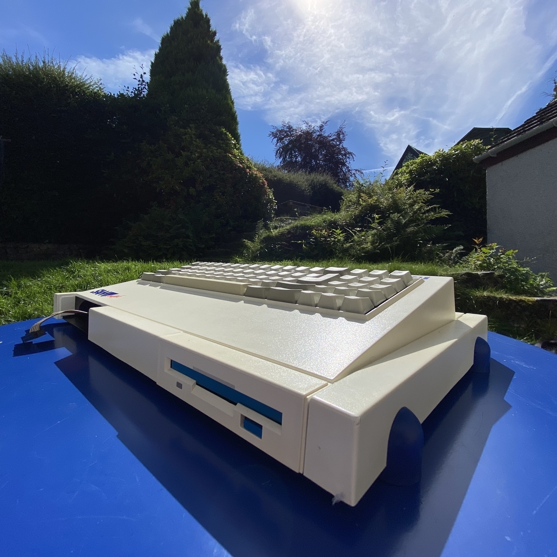 SAM Coupé computer on a garden table in bright direct sunshine