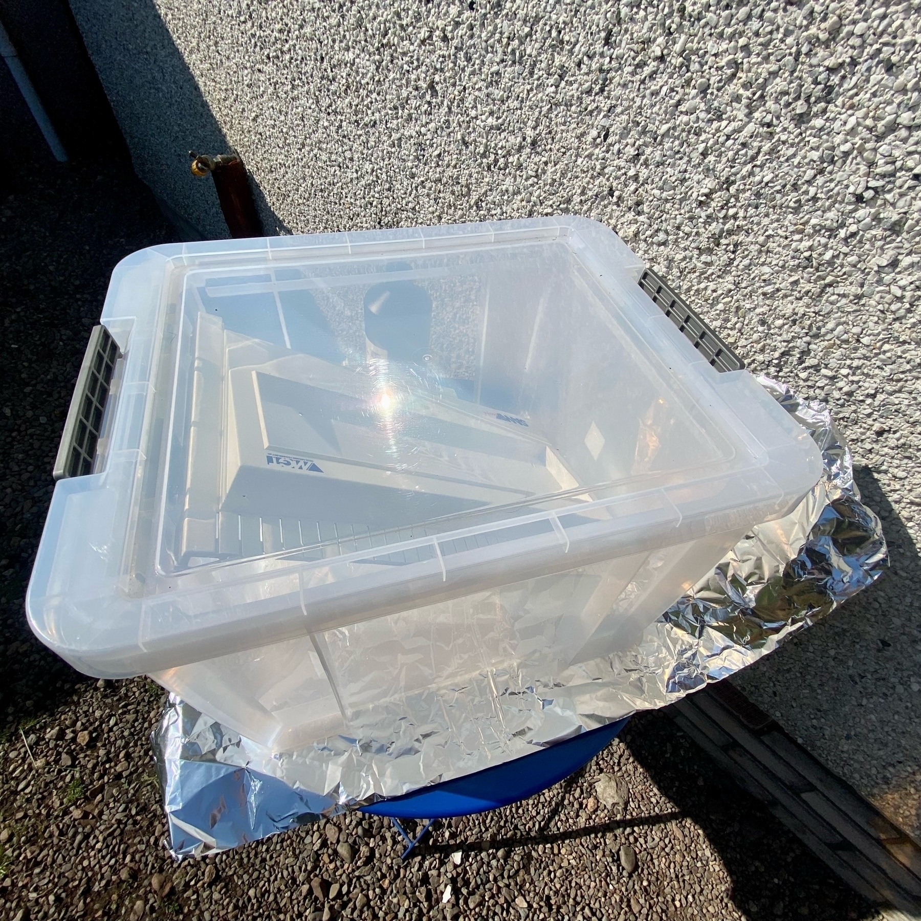 a large clear Perspex™ box in direct sunlight with a SAM Coupé top case inside, aluminium foil underneath, clear lid clipped on tightly