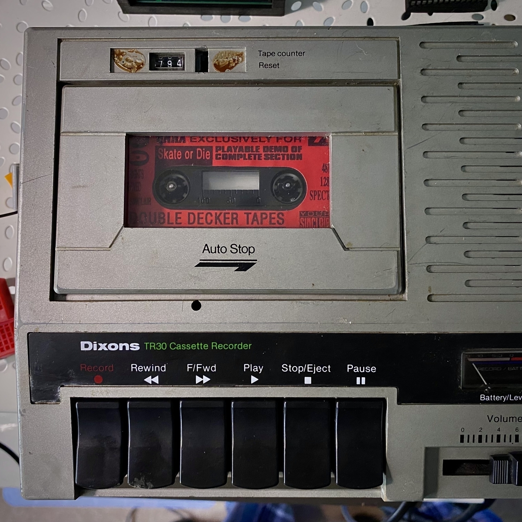 Overhead photo of the cassette recorder showing lots of patina from decades of wear and tear. It’s dusty, scratched and worn with a small faceplate around the tape counter missing. A red cassette tape can be seen through the deck window. The label reads: SKATE OR DIE; DOUBLE DECKER TAPES.