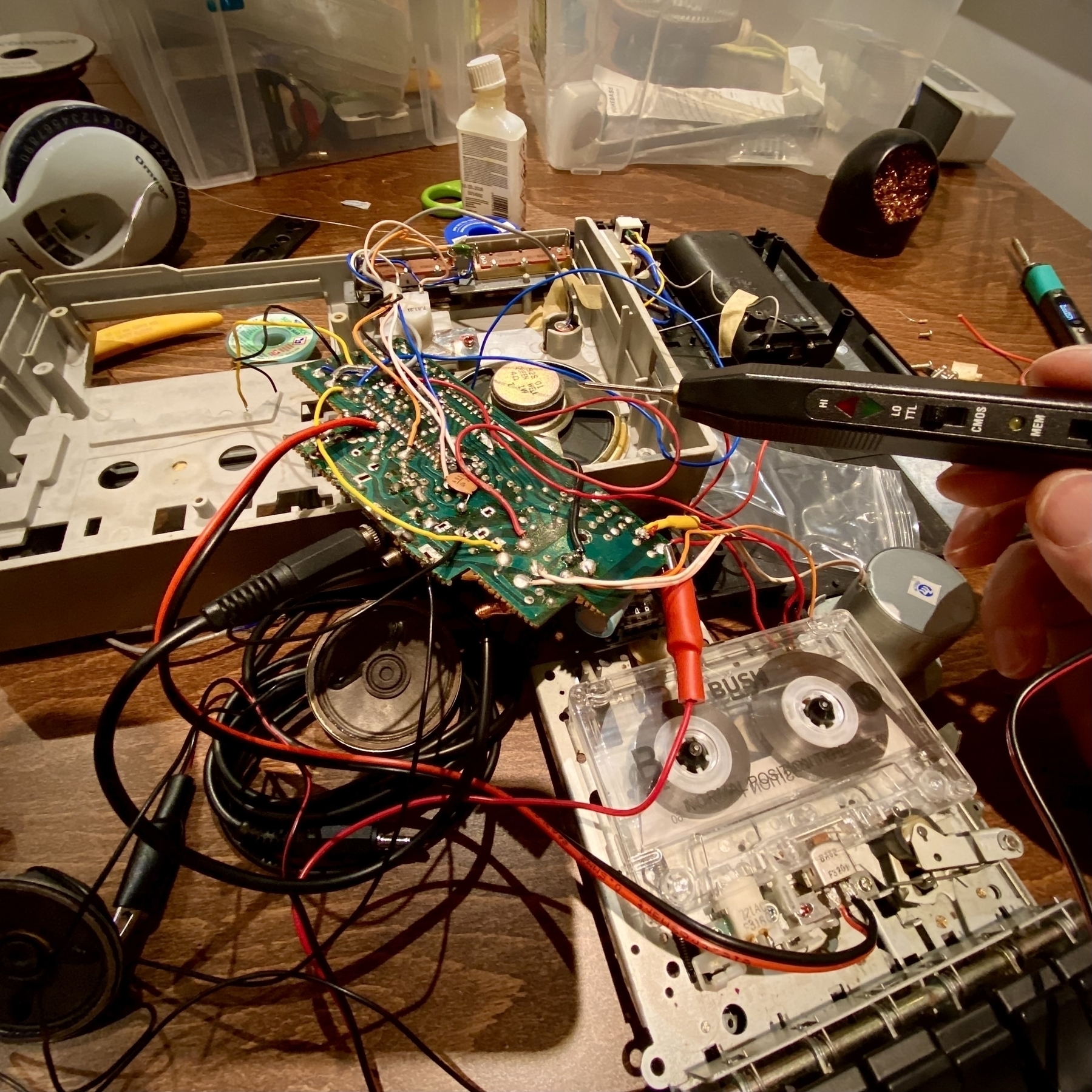 Photograph of a disassembled shoebox style cassette recorder. There is a cassette in the exposed mechanism and many wires all over the place. I’ve connected a logic probe for some reason. It’s playing Matchbox Twenty but you can’t hear it because this is a photograph.