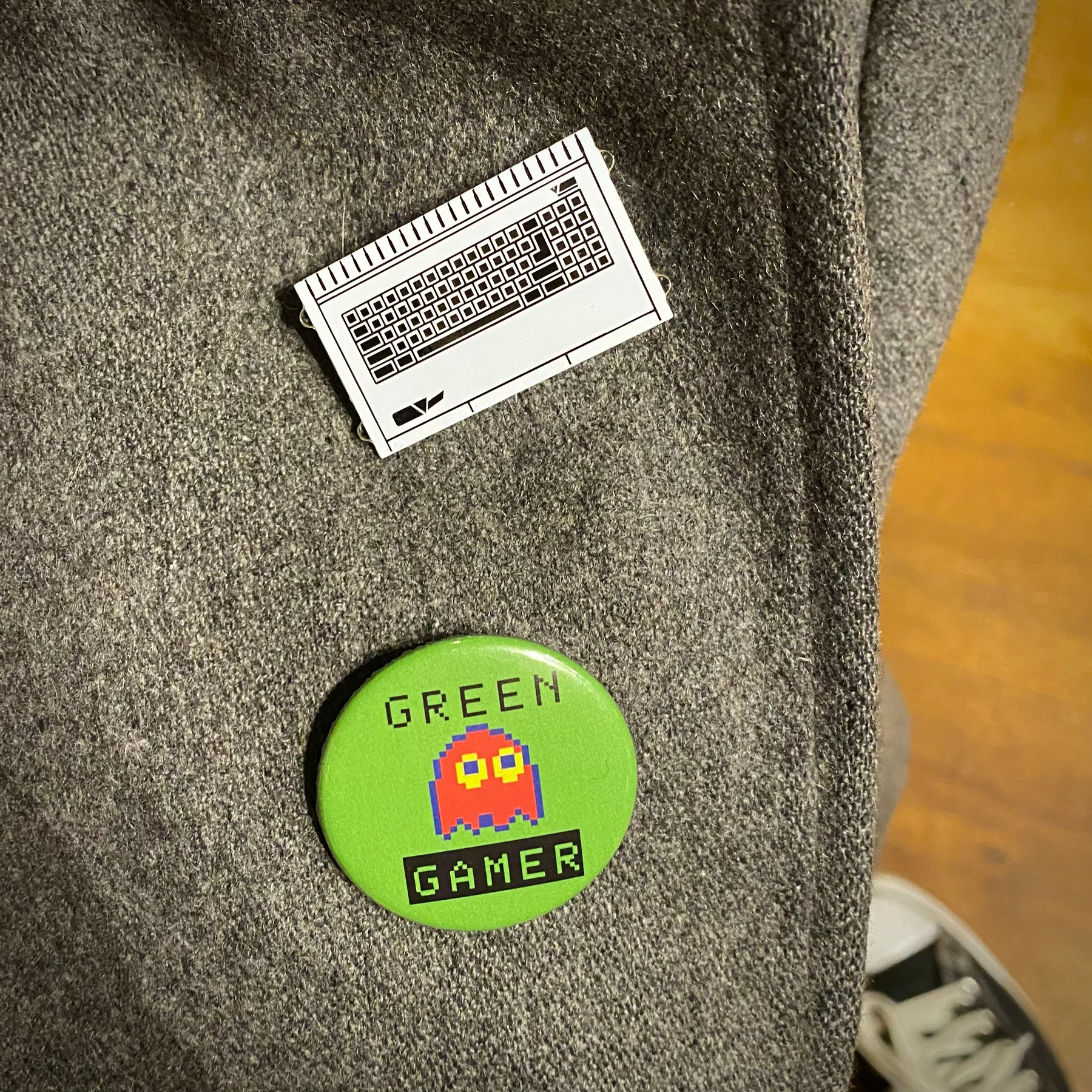 A SAM Coupé pin badge and a “green gamer” badge with a Pac-Man style ghost on the lapel of my jacket. 