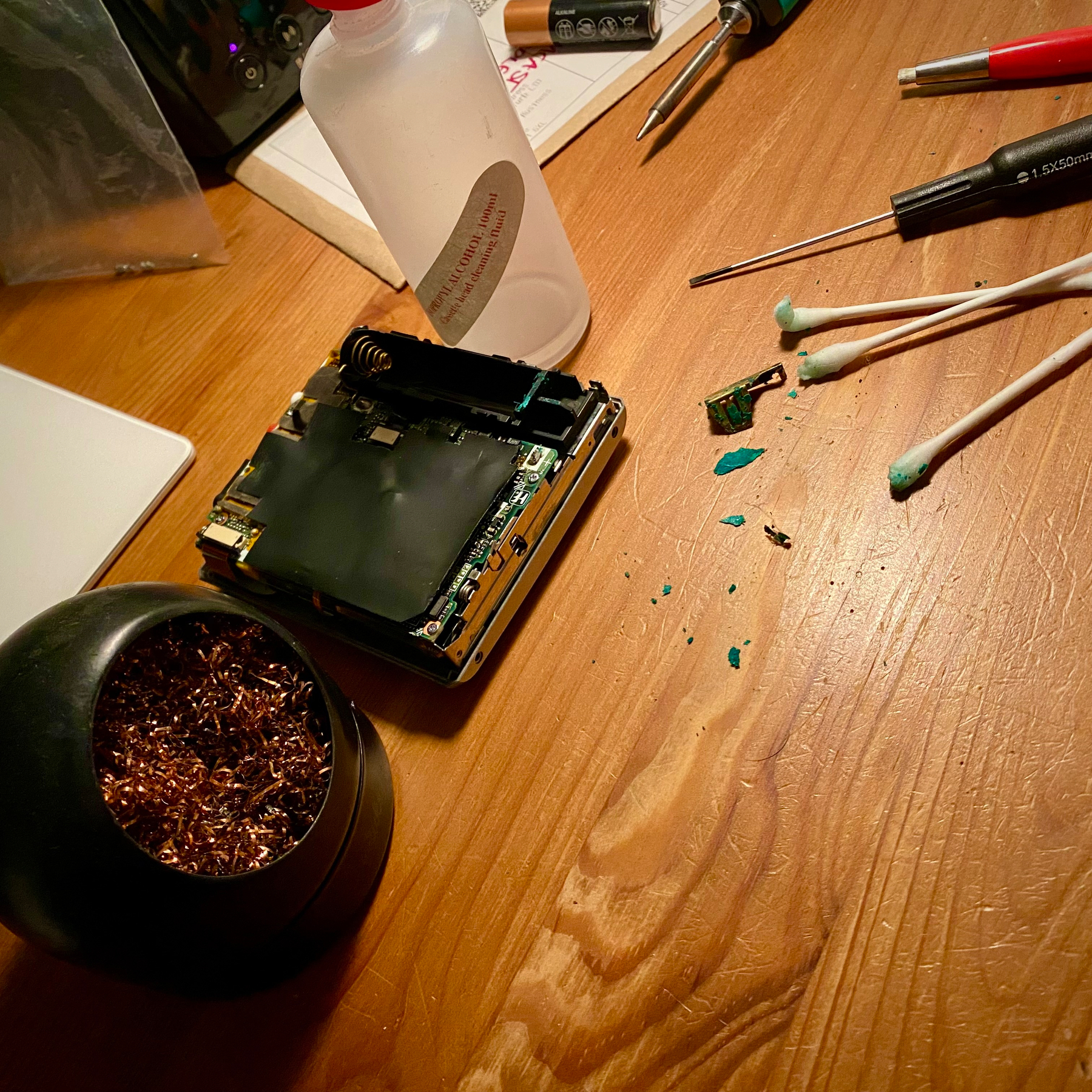 Partially disassembled Sony MiniDisc Walkman. The batter contacts are crusted green. Soldering tools and cotton buds have been used to start the repair.