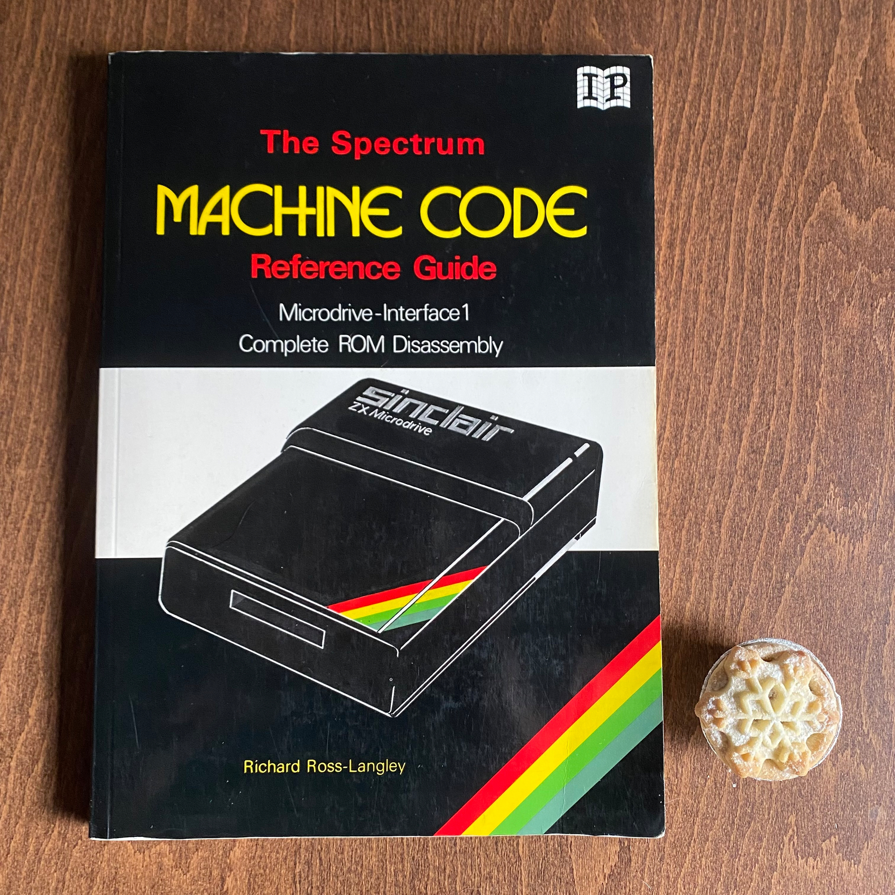 Photograph of a book titled “The Spectrum MACHINE CODE Reference Guide”, subtitled “Microdrive Interface 1 Complete ROM Disassembly”. Also pictured is a mince pie. 