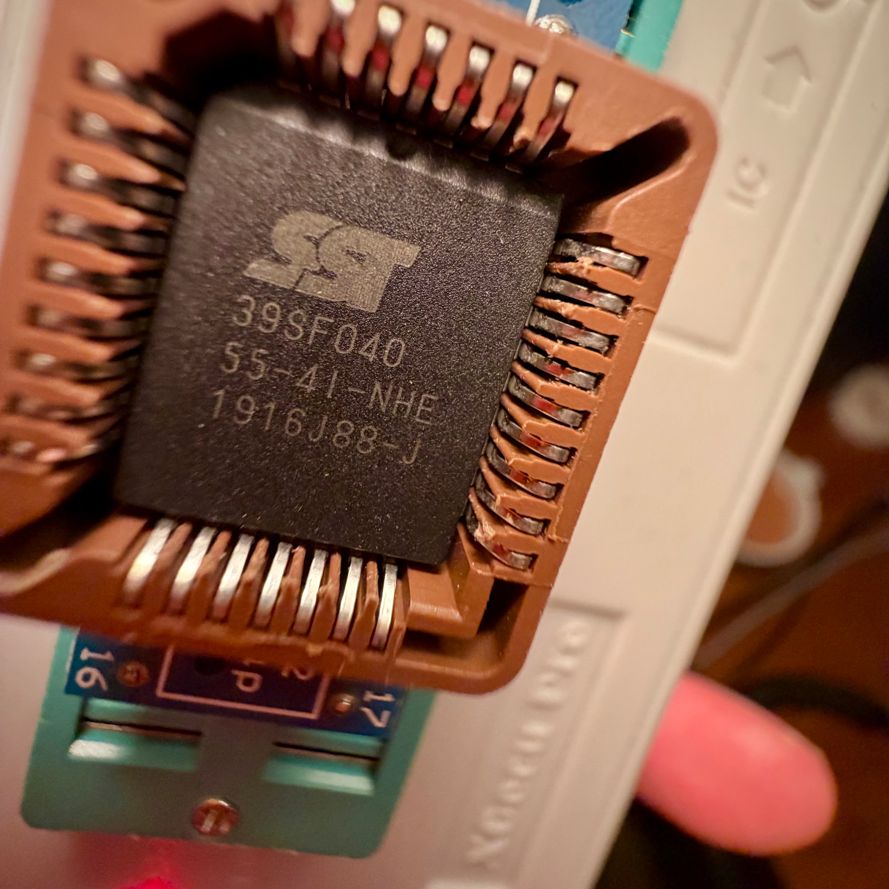Dramatic photo of a PLCC chip (SST39SF040 flash EEPROM) in a programming device.