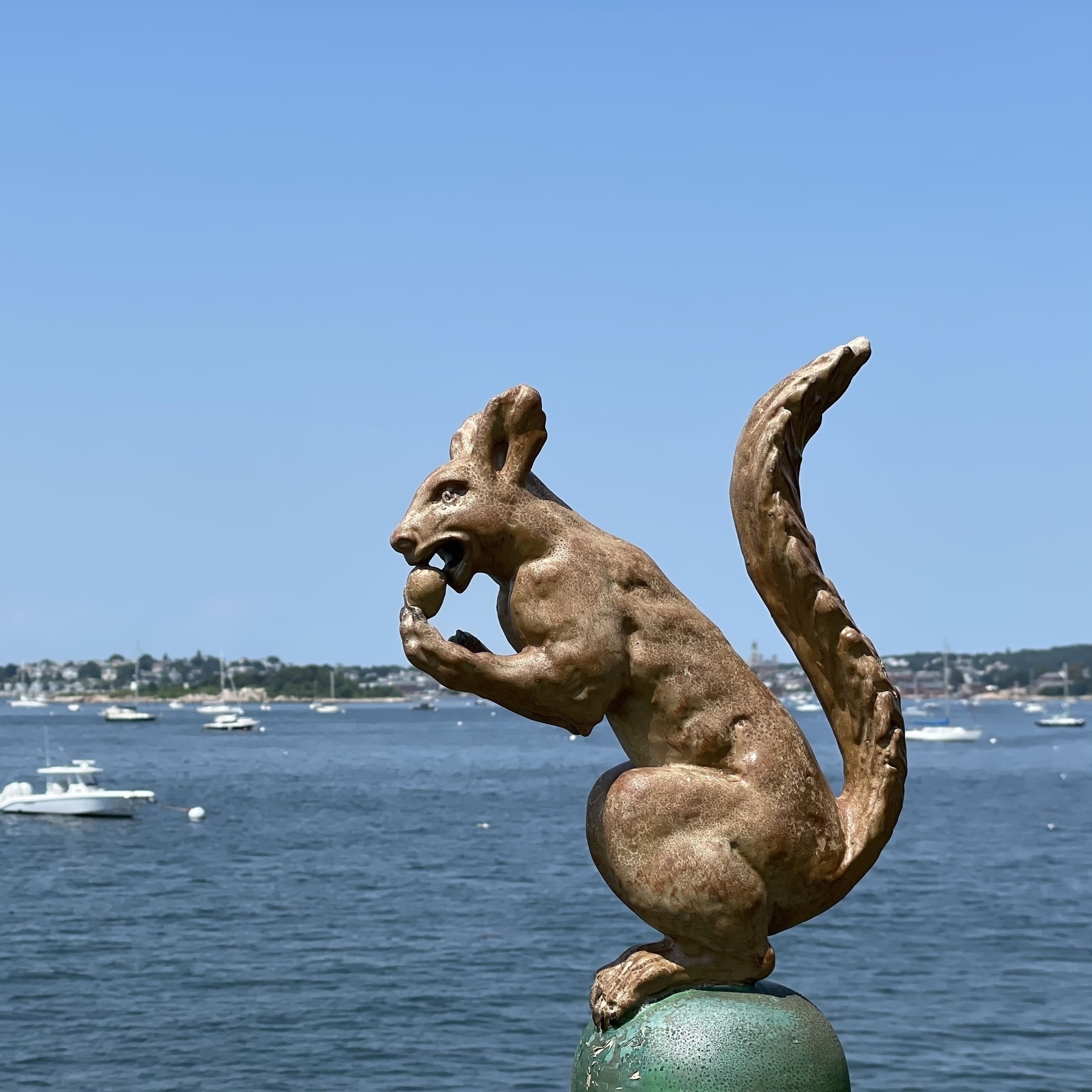 Squirrel with nut decorative finial in foreground and boats in harbor beyond