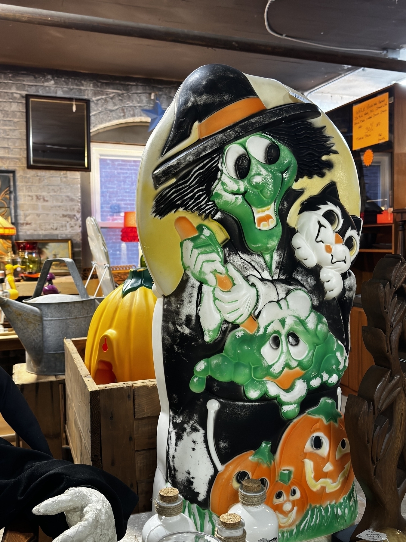 Vintage plastic light-up witch with a green face, a black cat, a bubbling cauldron, and orange jack-o-lanterns at the base