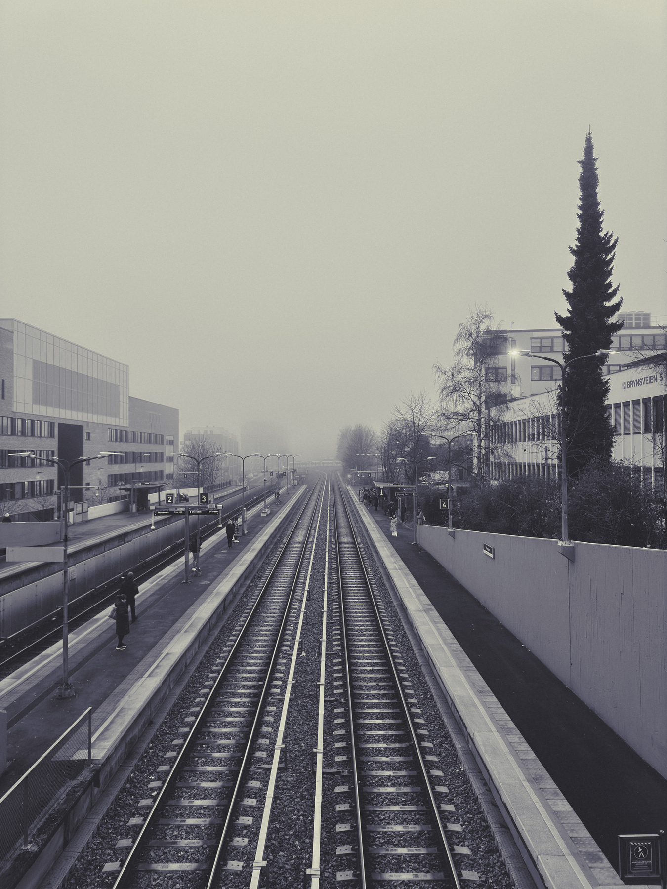 A foggy, almost empty subway station platform with tracks extending into the distance.