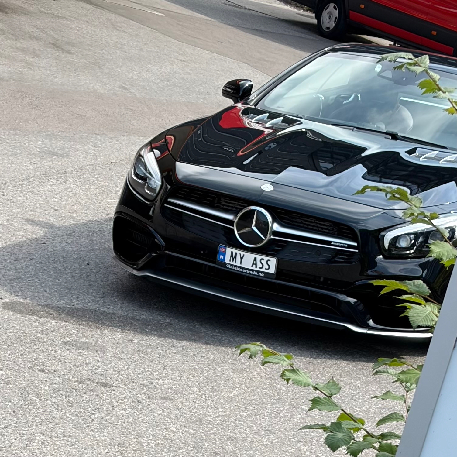 En svart Mercedes-bil med en spesiell registreringsskilt som sier MY ASS står parkert på en asfaltvei.