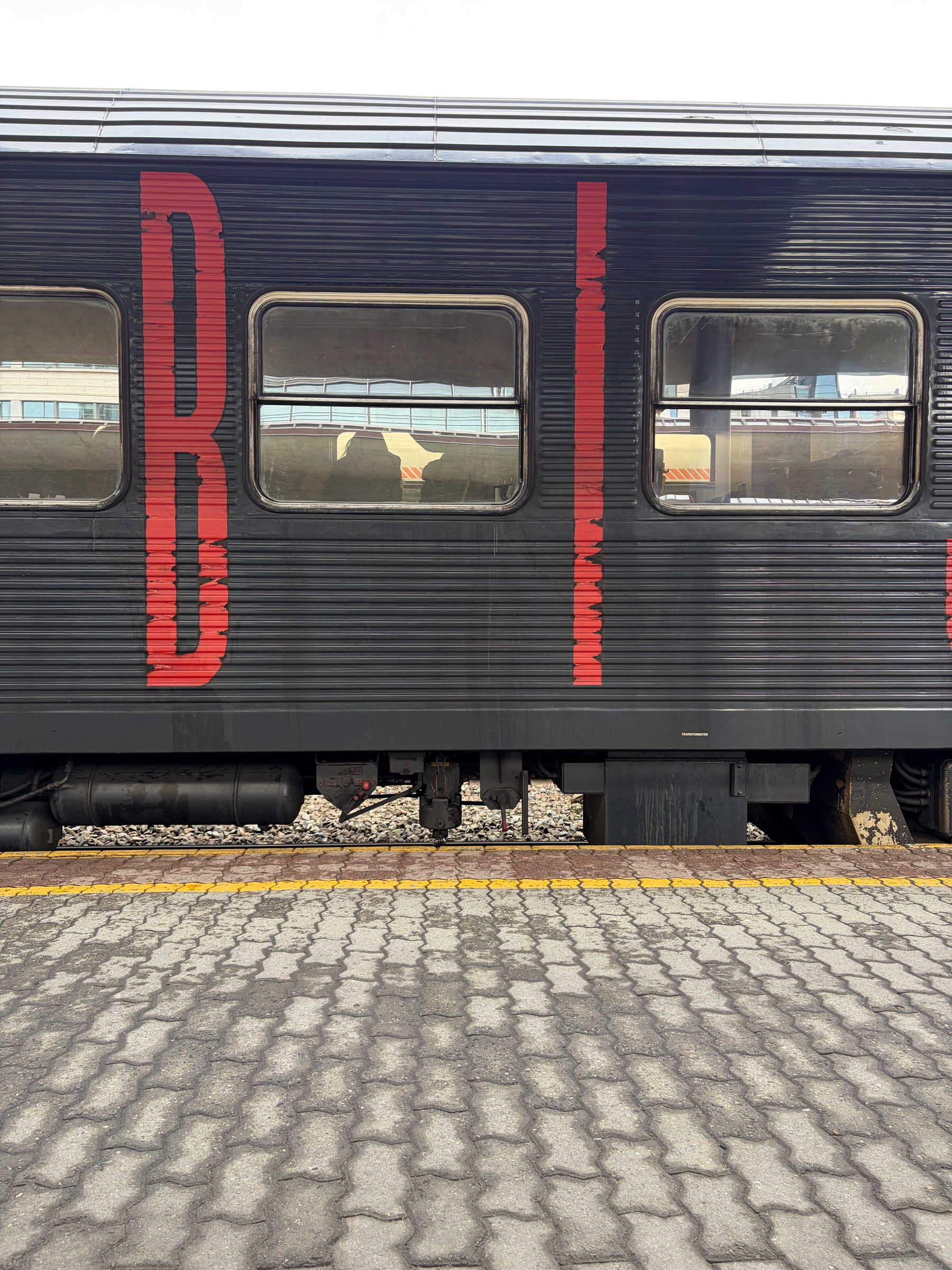 Et tog med røde bokstaver står ved en plattform med gule sikkerhetslinjer.