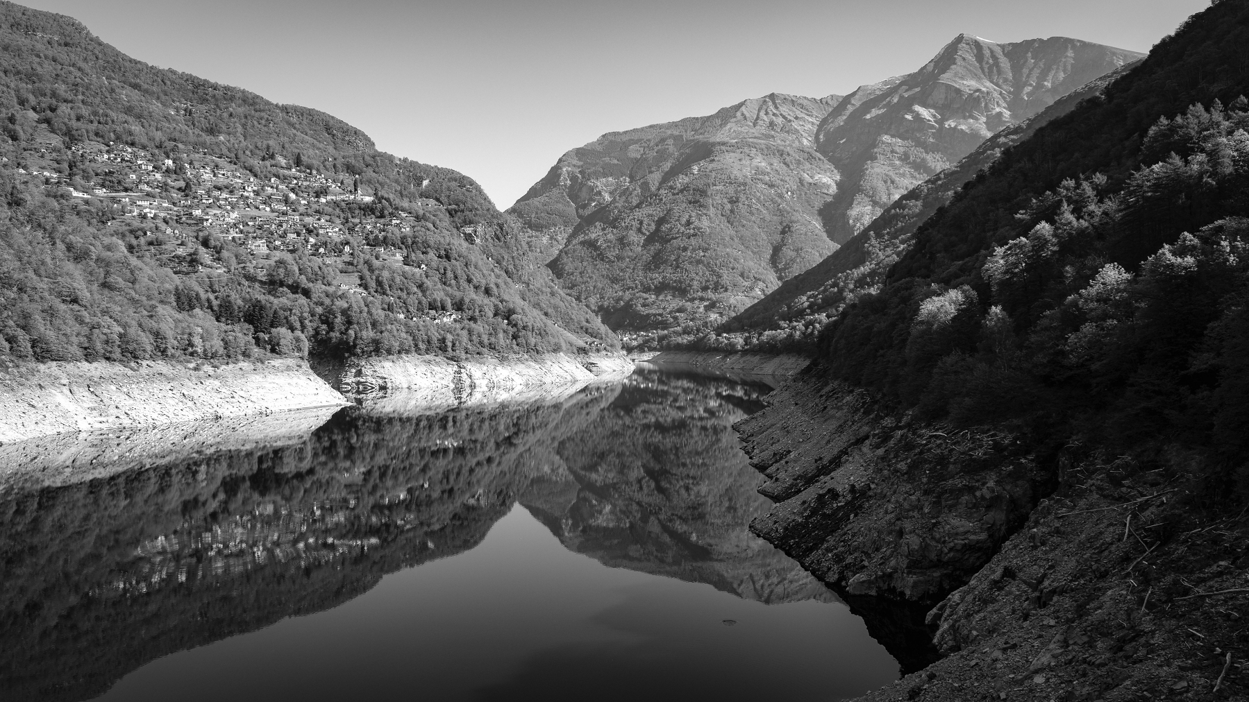 Auto-generated description: Un lac entouré de montagnes avec une eau calme reflétant les paysages environnants.
