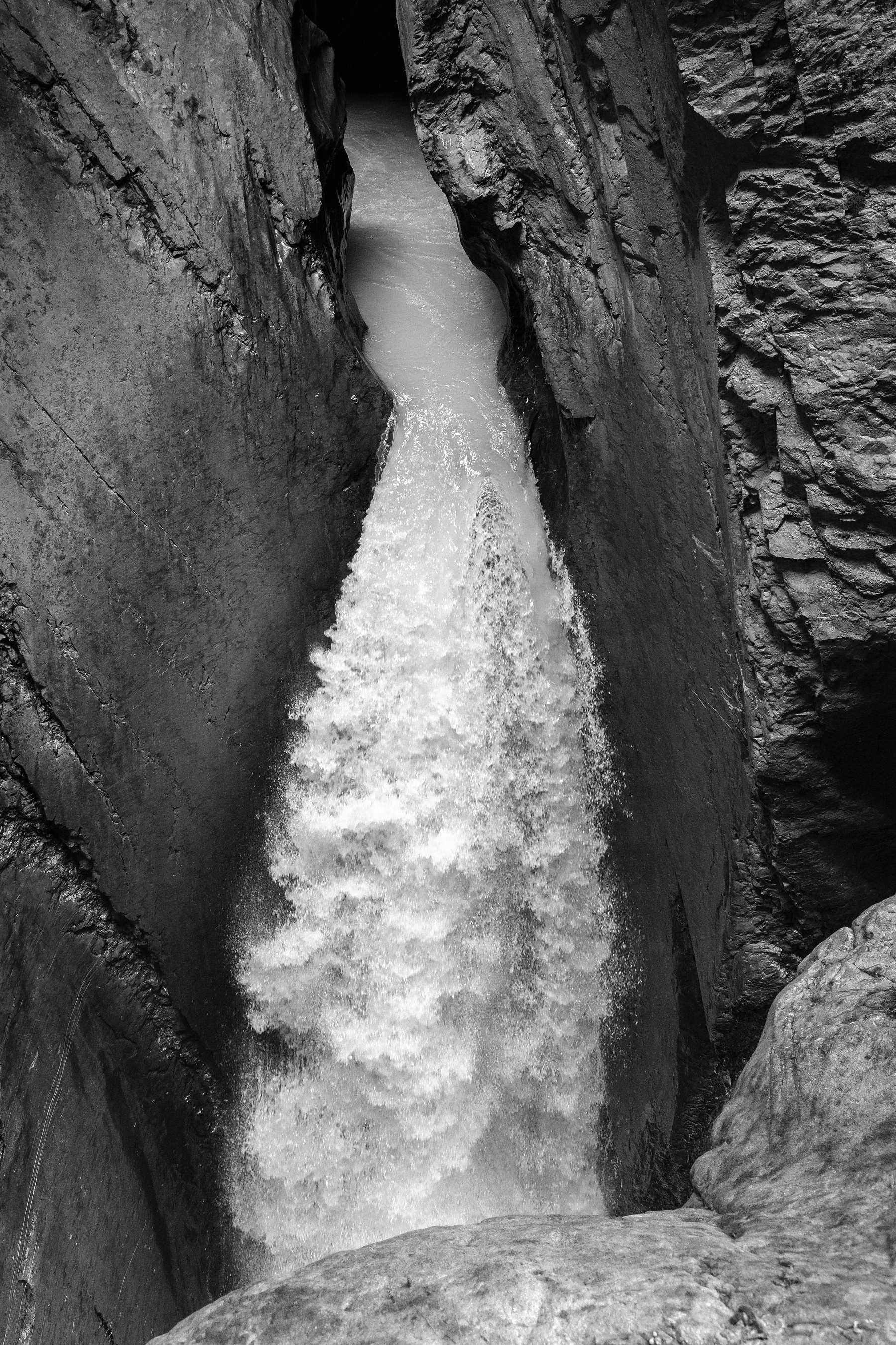 Auto-generated description: Une cascade puissante s'écoule avec force à travers un étroit goulet rocheux.