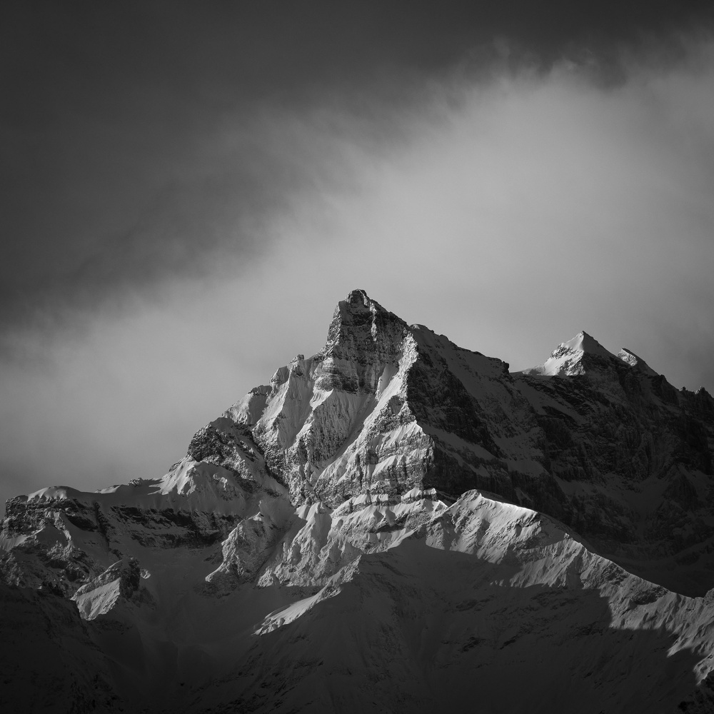 Un majestueux paysage montagneux enneigé domine sous un ciel dramatique.