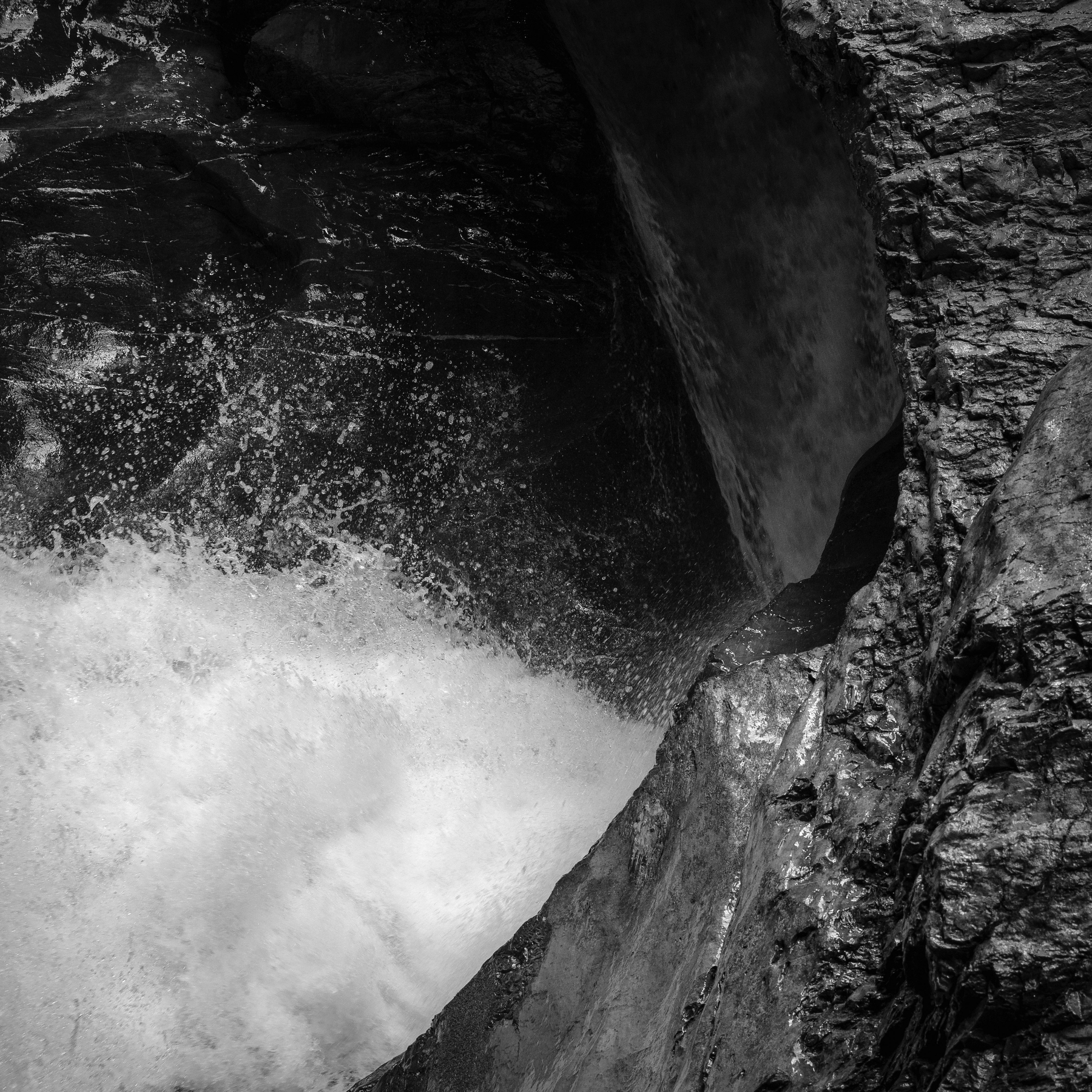 Auto-generated description: Une cascade en noir et blanc tombe sur des rochers escarpés.