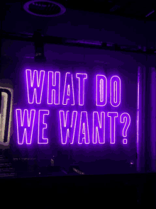 Neon purple letters spelling WHAT DO WE WANT?