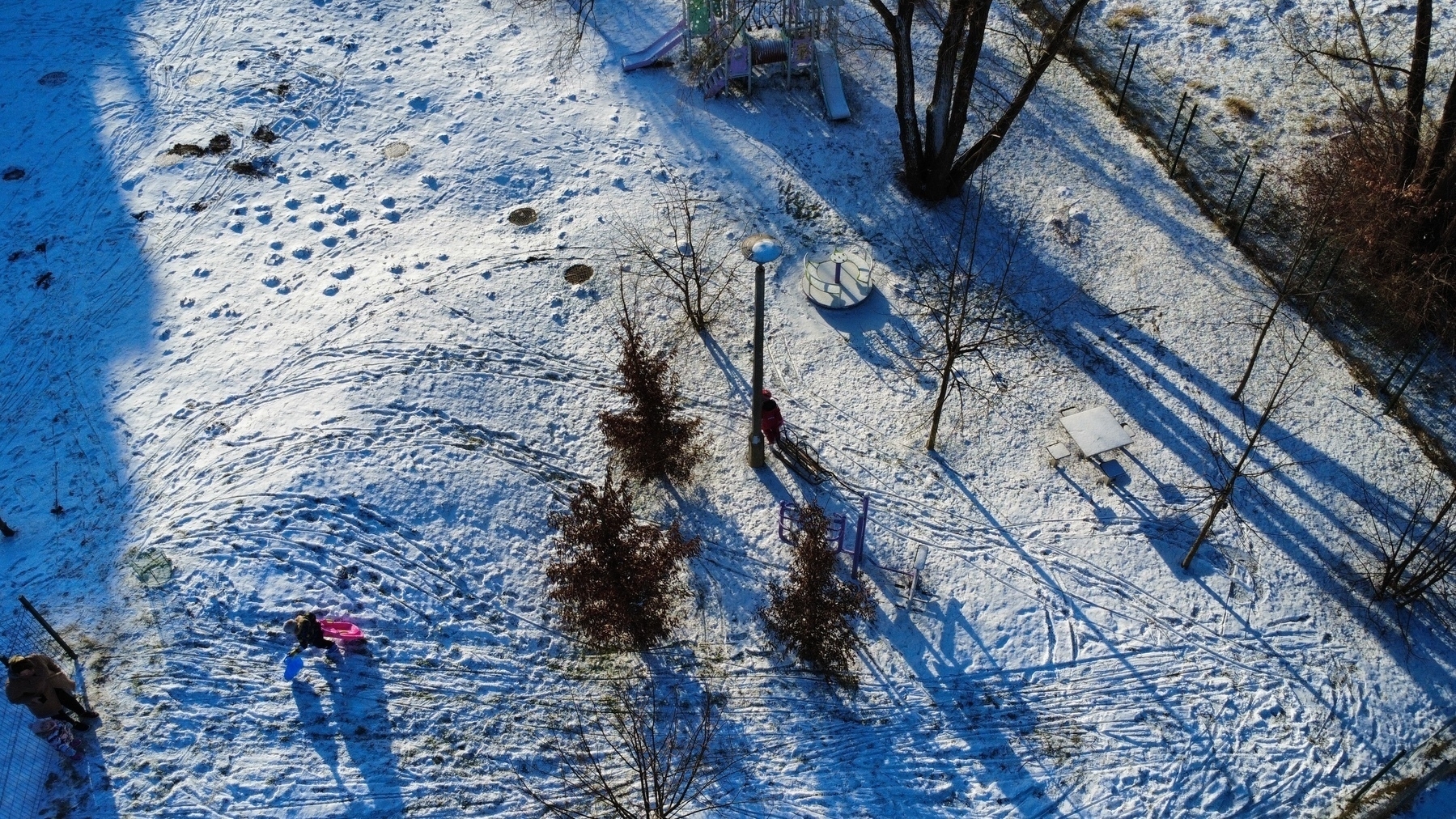 Drone photo of kids sledging down a snowy hill. 