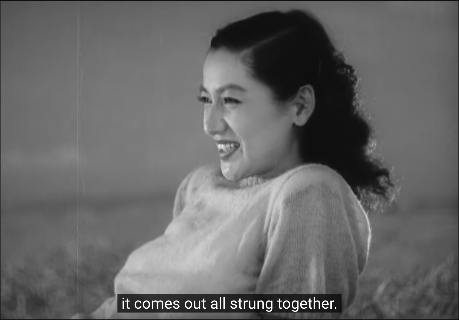 a still from ozu's "late spring" of noriko (setsuko hara) at the beach with hattori (jun usami; off-screen), where noriko is smiling, looking away from the camera, and is saying "it comes out all strung together."