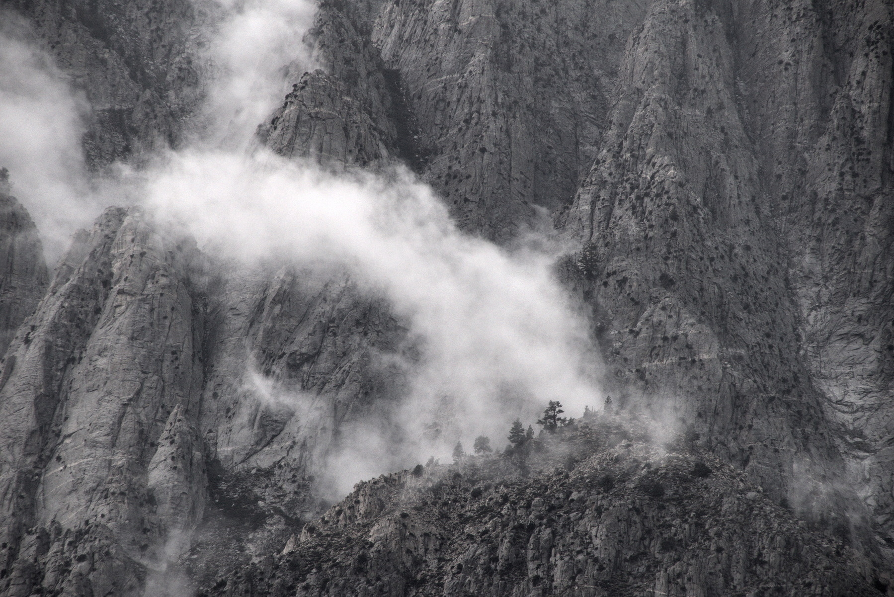 Wispy clouds nestling in the rocks of a mountain cliff.