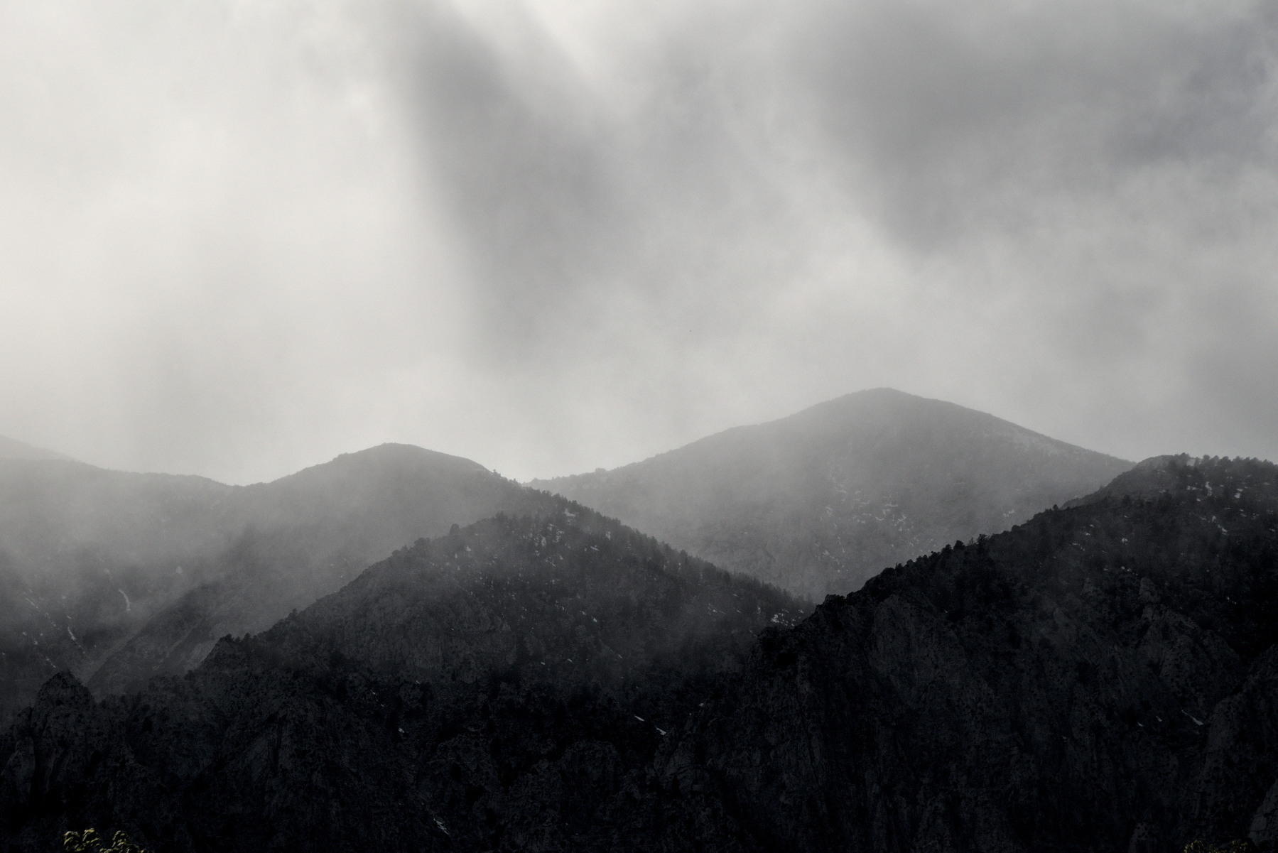 Layered mountain ranges, fading from black to grey.