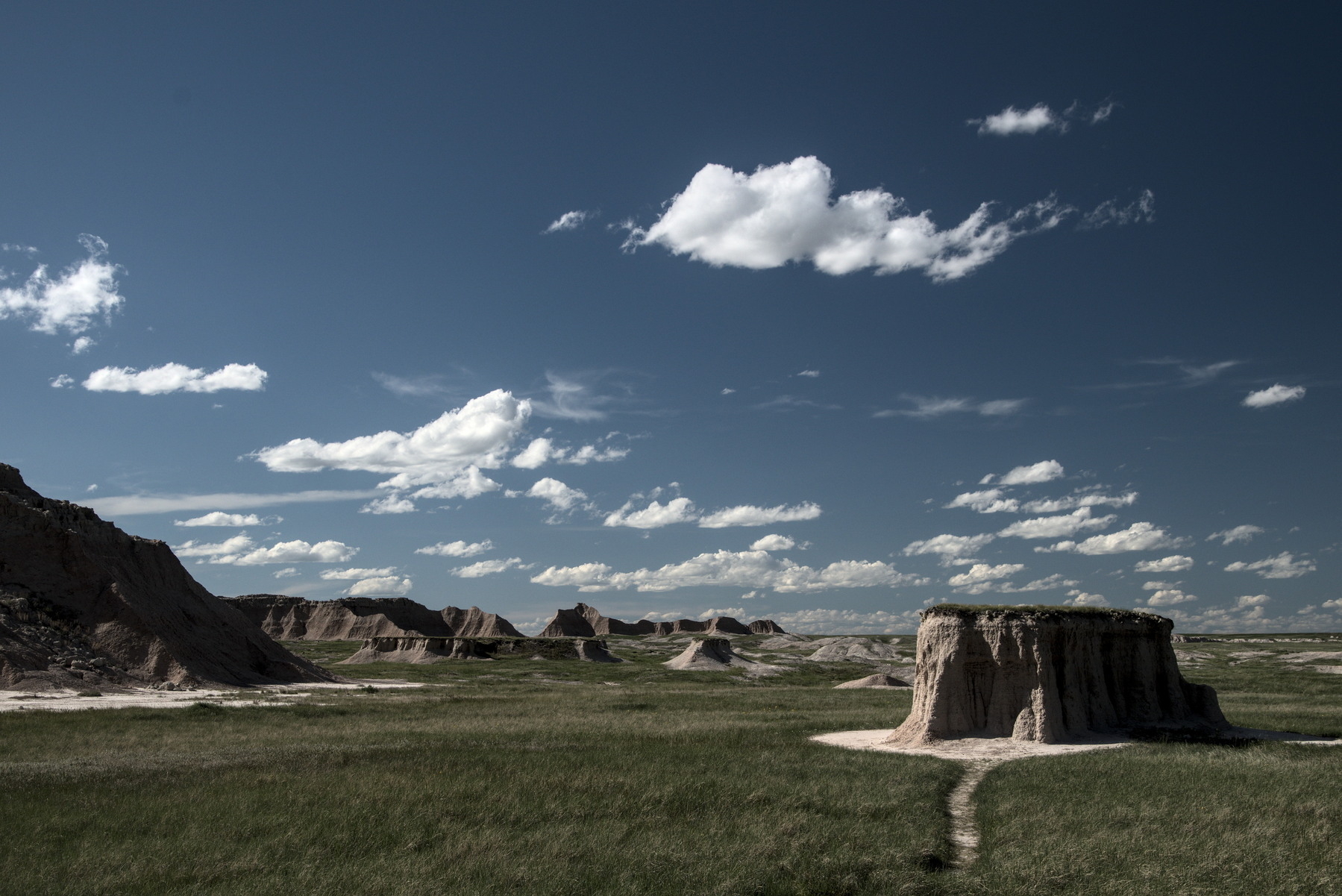 Grasslands interrupted by eroding towers and mesas of soft rock. 