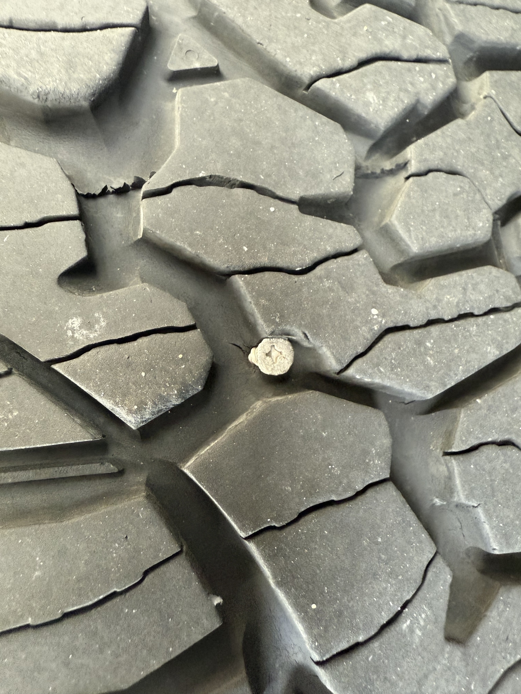 Close-up of a rugged tire tread with a small rock lodged in one of the grooves.