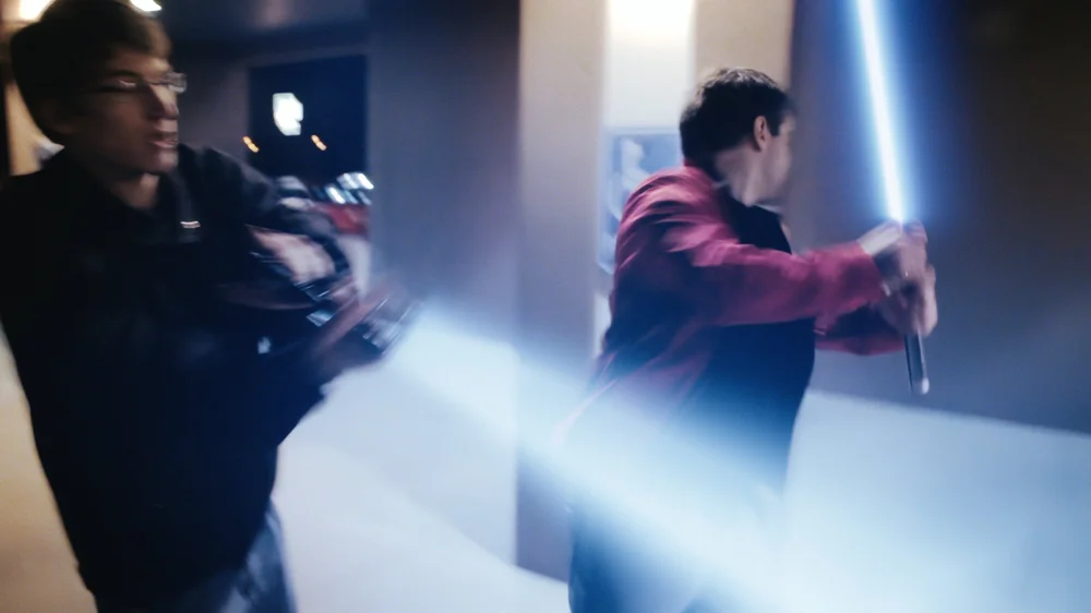 Two people are engaged in a dynamic scene with glowing lightsaber-like effects.