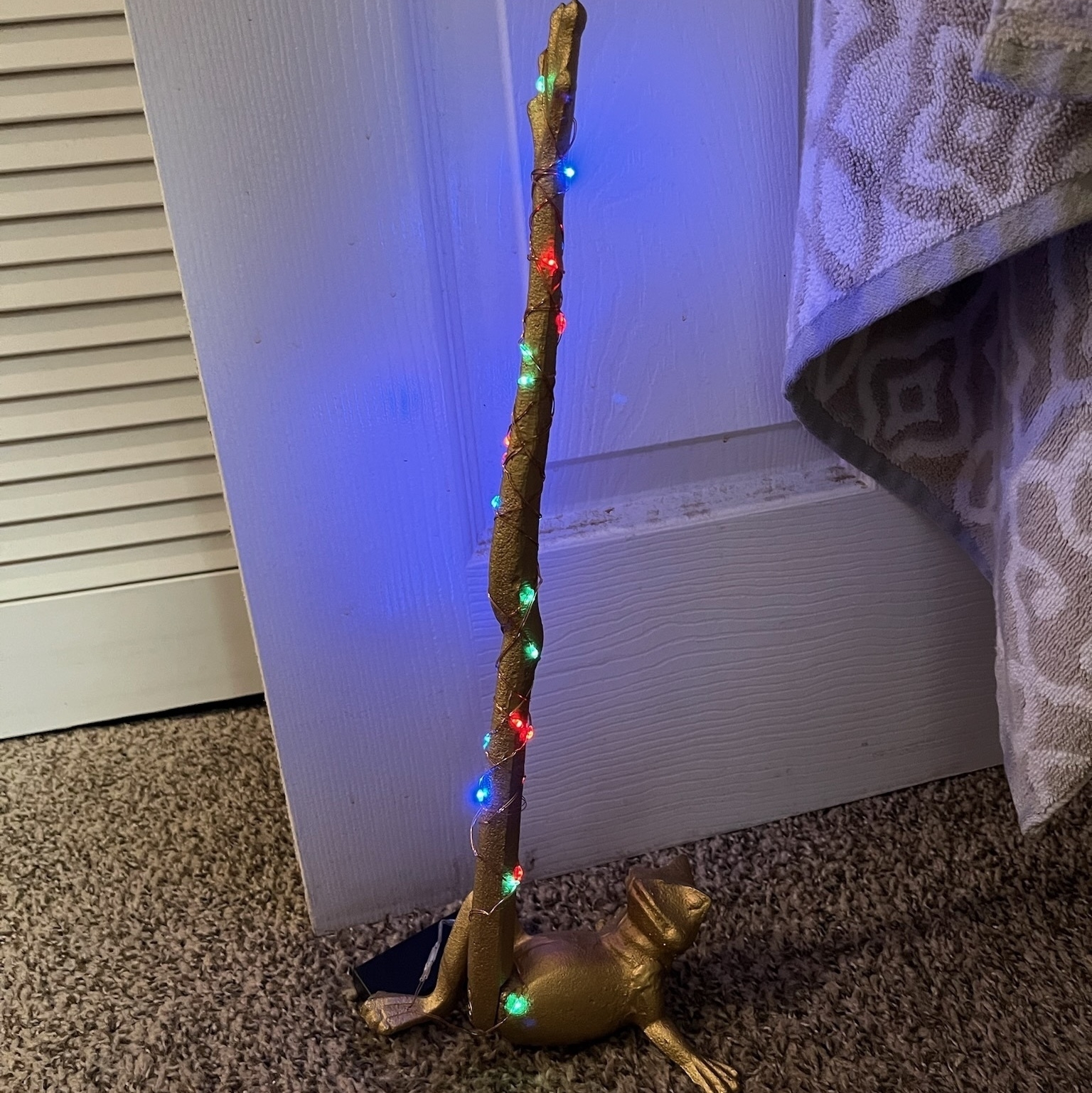 gold frog with leg straight up with Christmas lights. 
