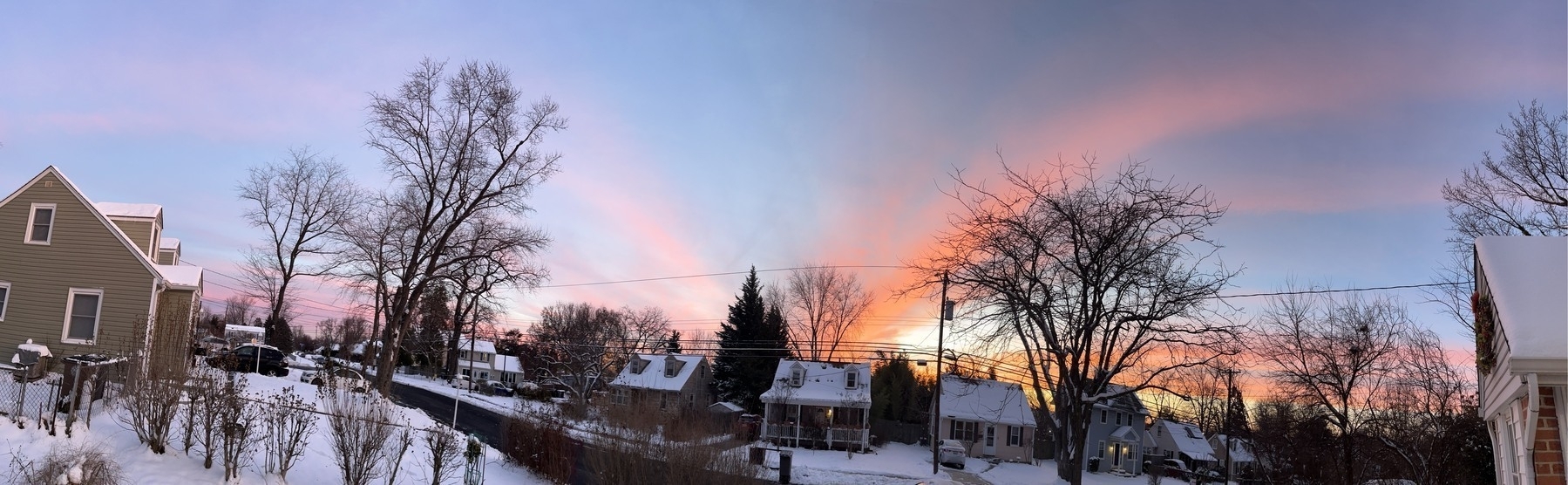 A sunset with stripes of pinks and purples and reds across a gray winter sky. 