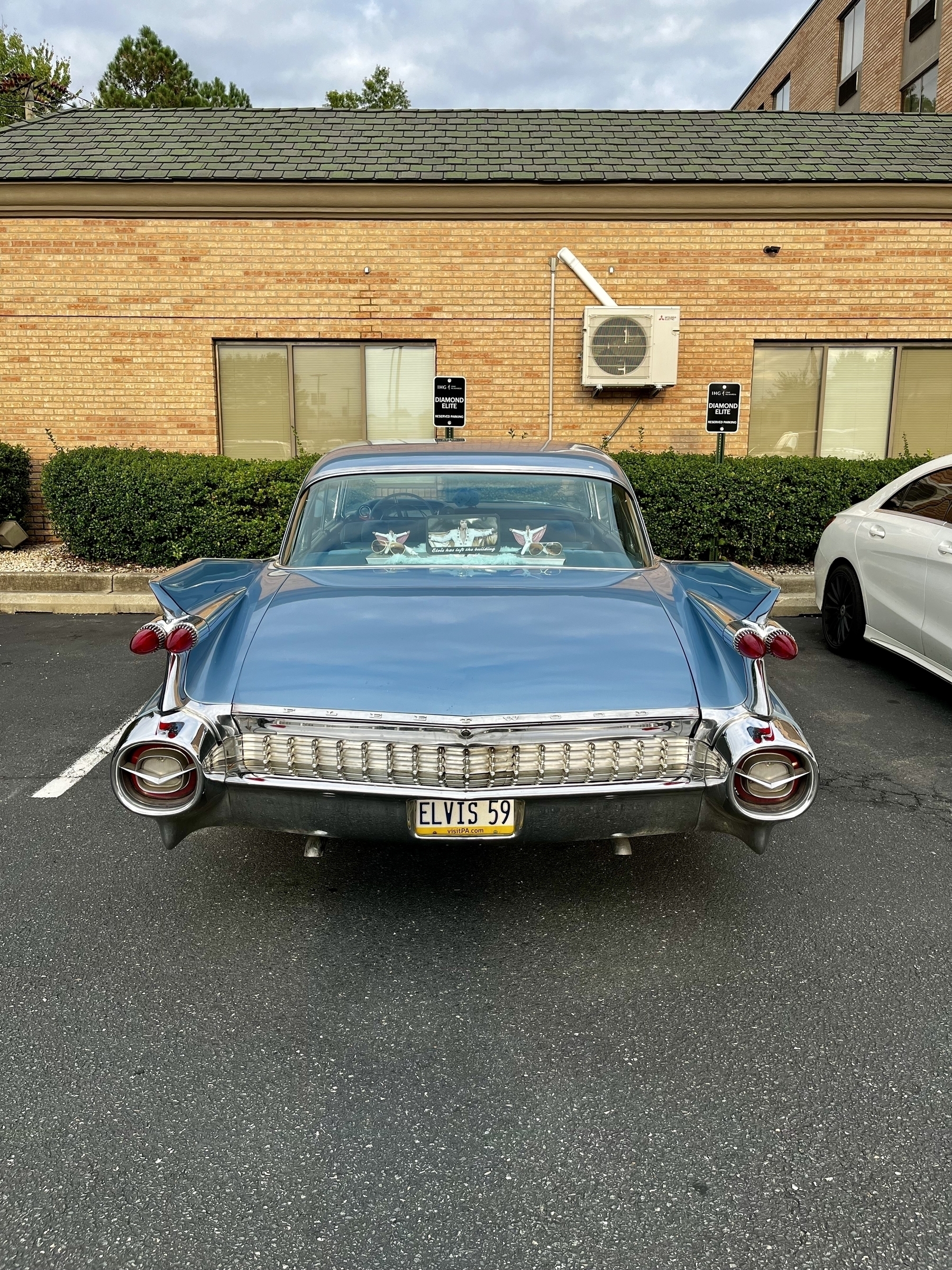 A vintage blue Cadillac parked with a license plate reading “ELVIS 59” in a spot for Diamond Elite members. 