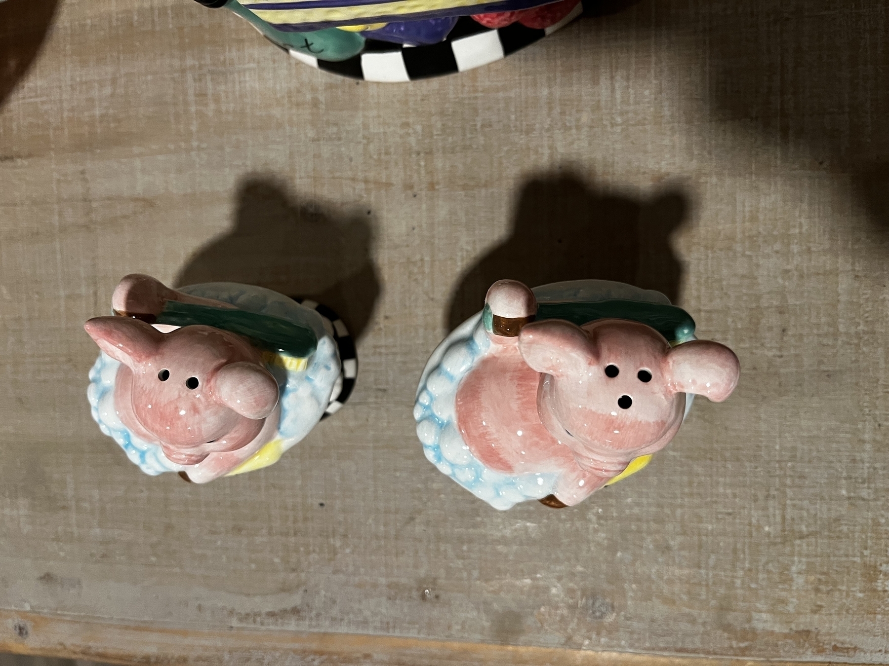 Two ceramic pig figures sit with holes in top of their heads for salt and pepper. 