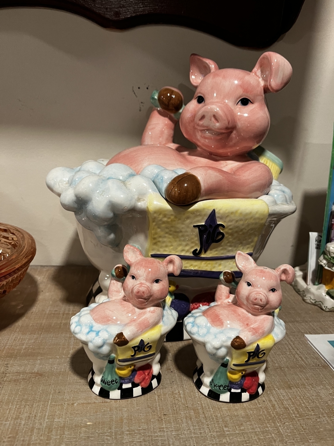 Ceramic figures of three pigs in bathtubs, with the largest opens up as a cookie jar and the two smaller pigs with holes in their heads for salt and pepper.