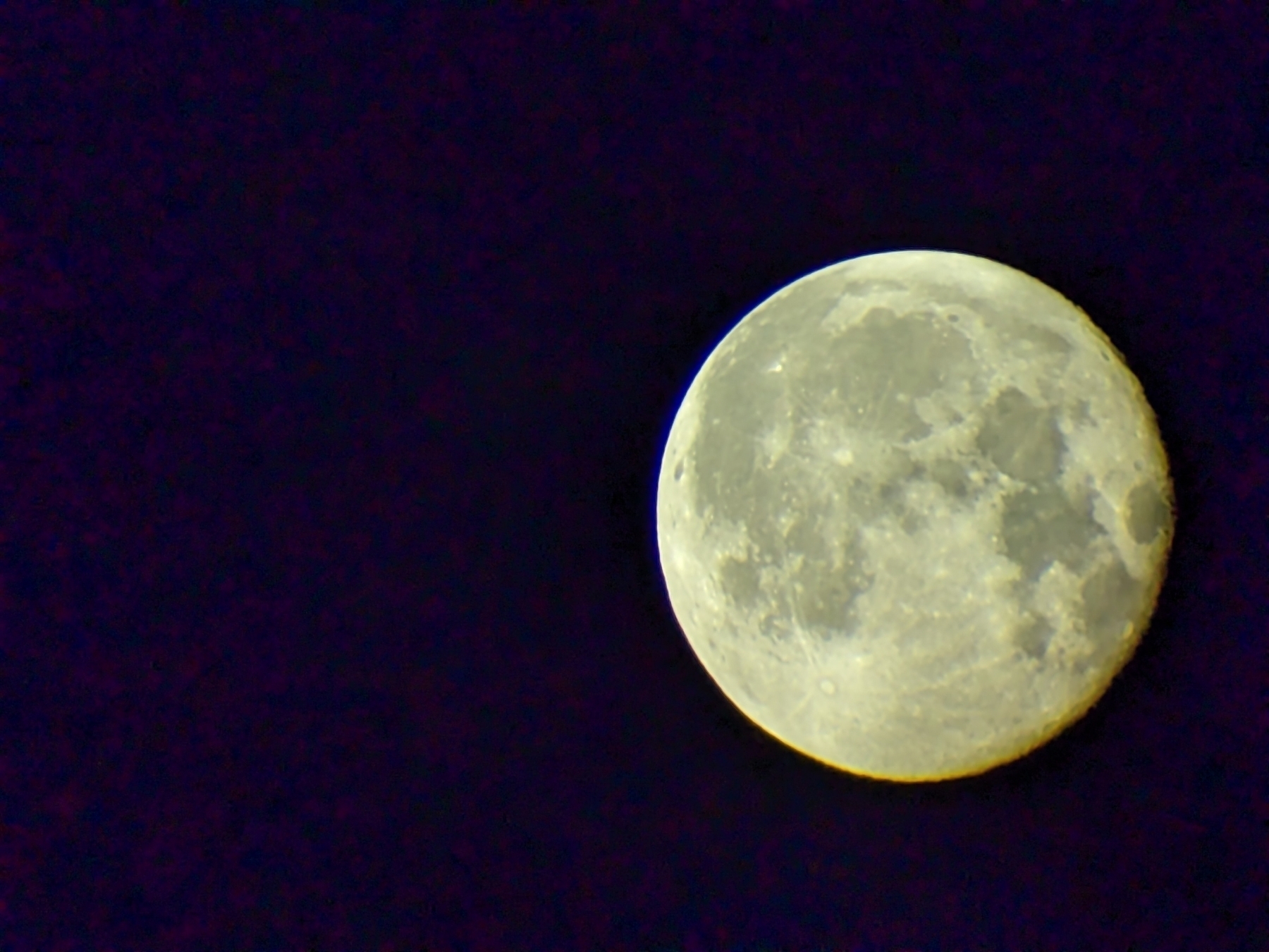 A nearly full moon with visible craters against a dark night sky.