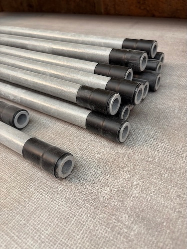 Several long, cylindrical objects with dark ends are neatly arranged in a bundle on a textured surface.