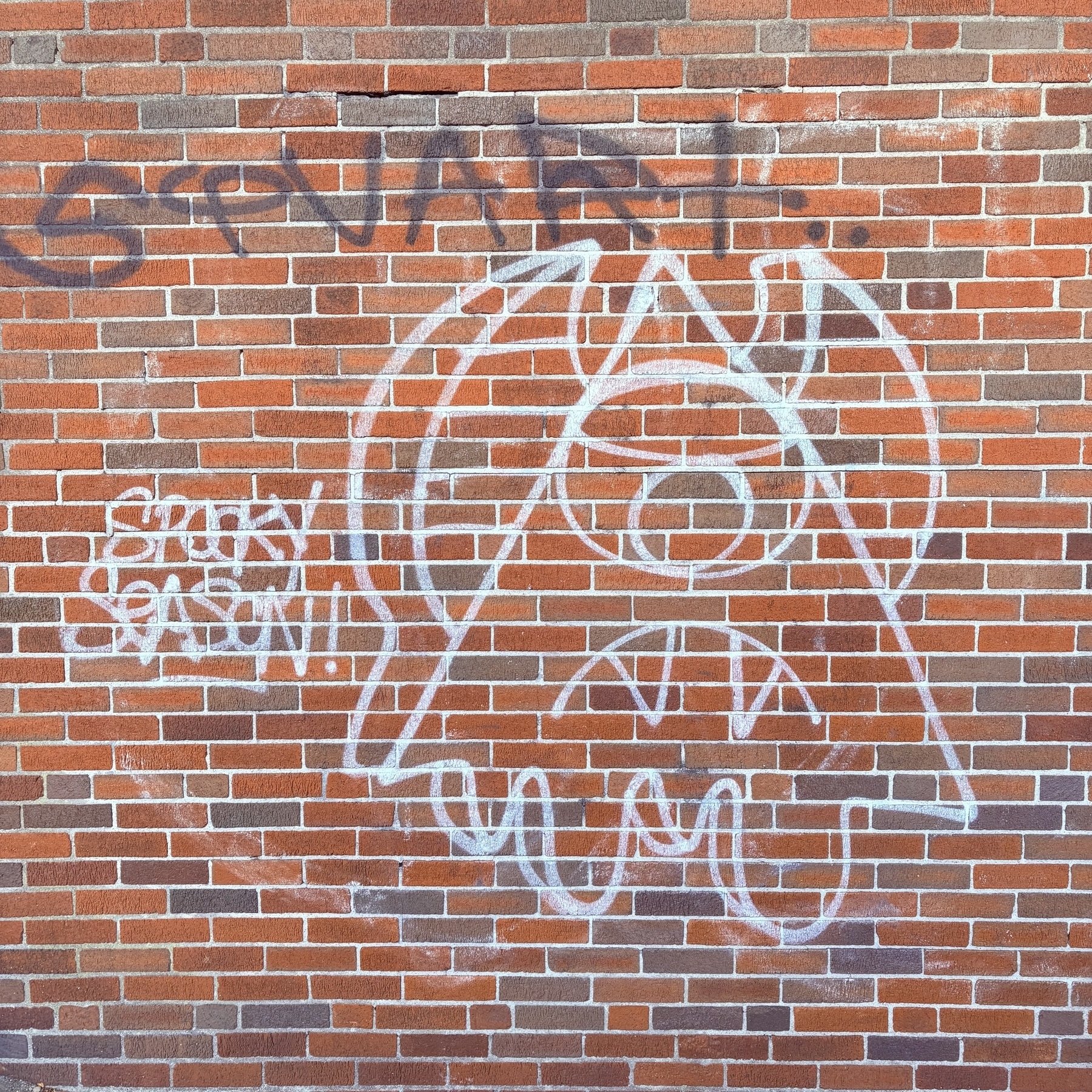 On a brick wall, a white line-drawing triangle monster with horns, a toothed maw, and one eye floats. To its left, “SPOOKY SEASON!” is written in the same white paint. 