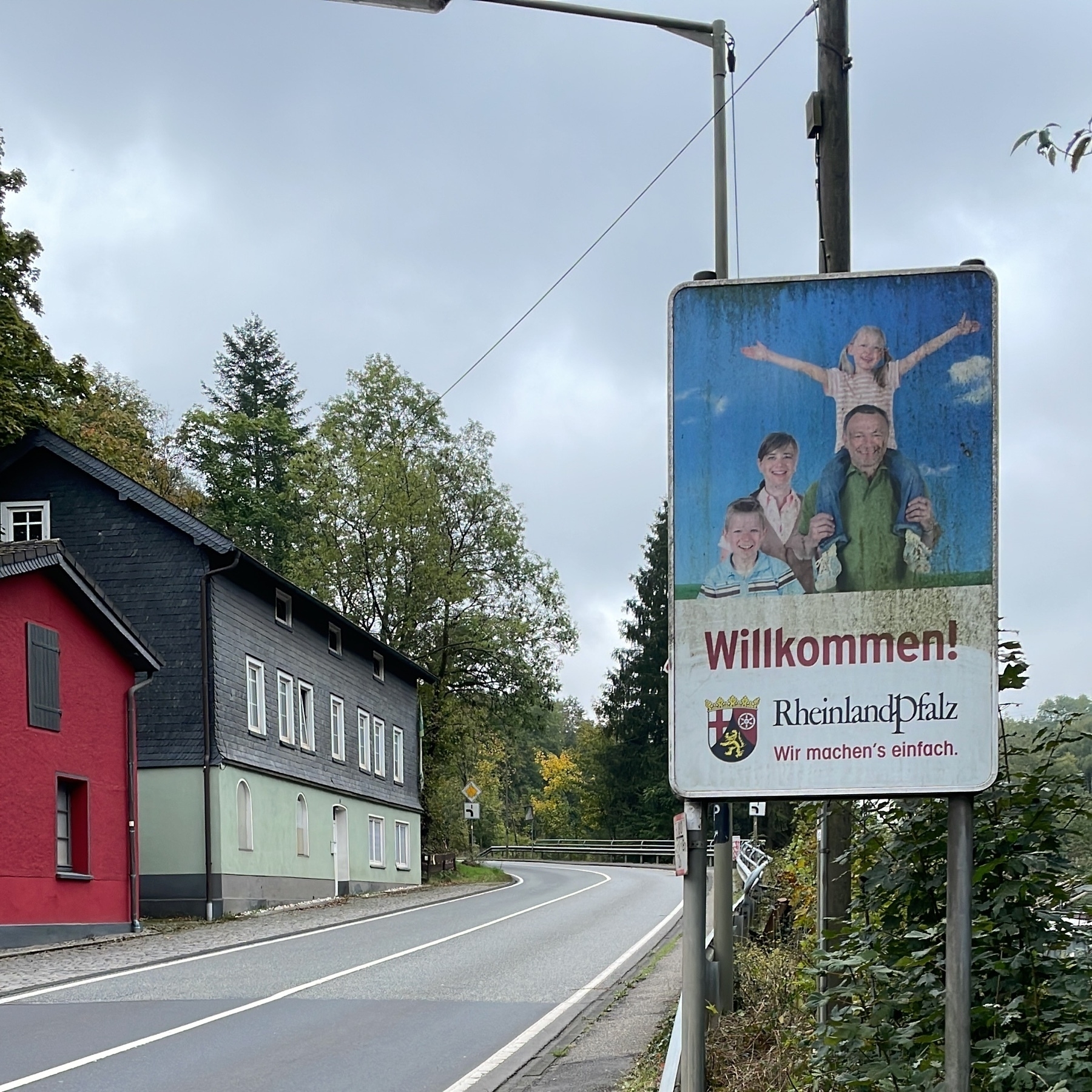 Willkommen Rheinland-Pfalz sign with a family and the slogan “wir machens einfach“ – “we just do it/we make it easy” wordplay. the red and black coat of arms is also shown.