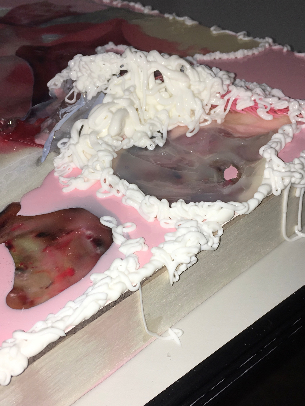 A book is covered in layers of wax or a similar substance with white, pink, and translucent colors.