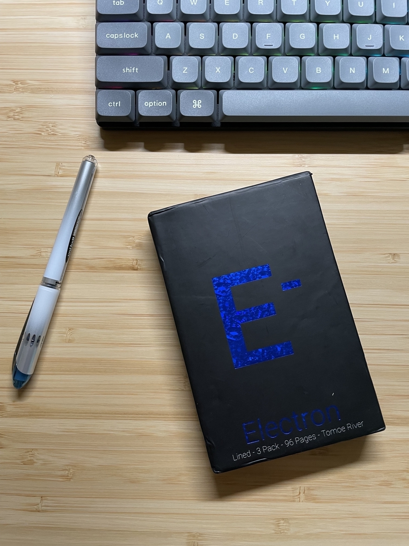 Electron pocket notebook from Element, with a uni-ball pen and a Keychron K3 keyboard