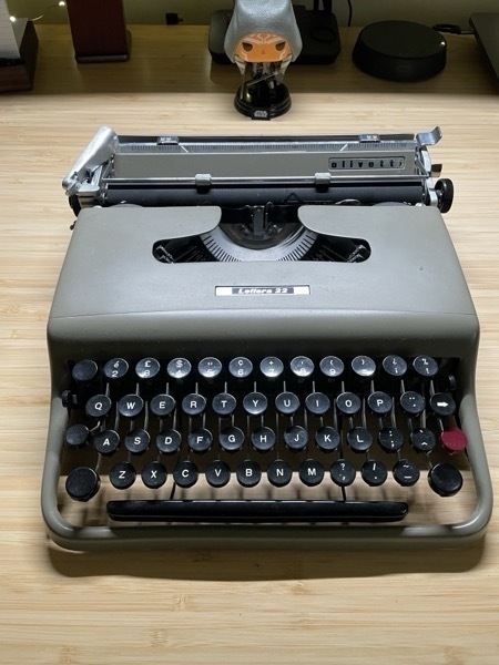 Olivetti Lettera 22 typewriter sitting on a bamboo desk with an Ahsoka bobblehead behind it