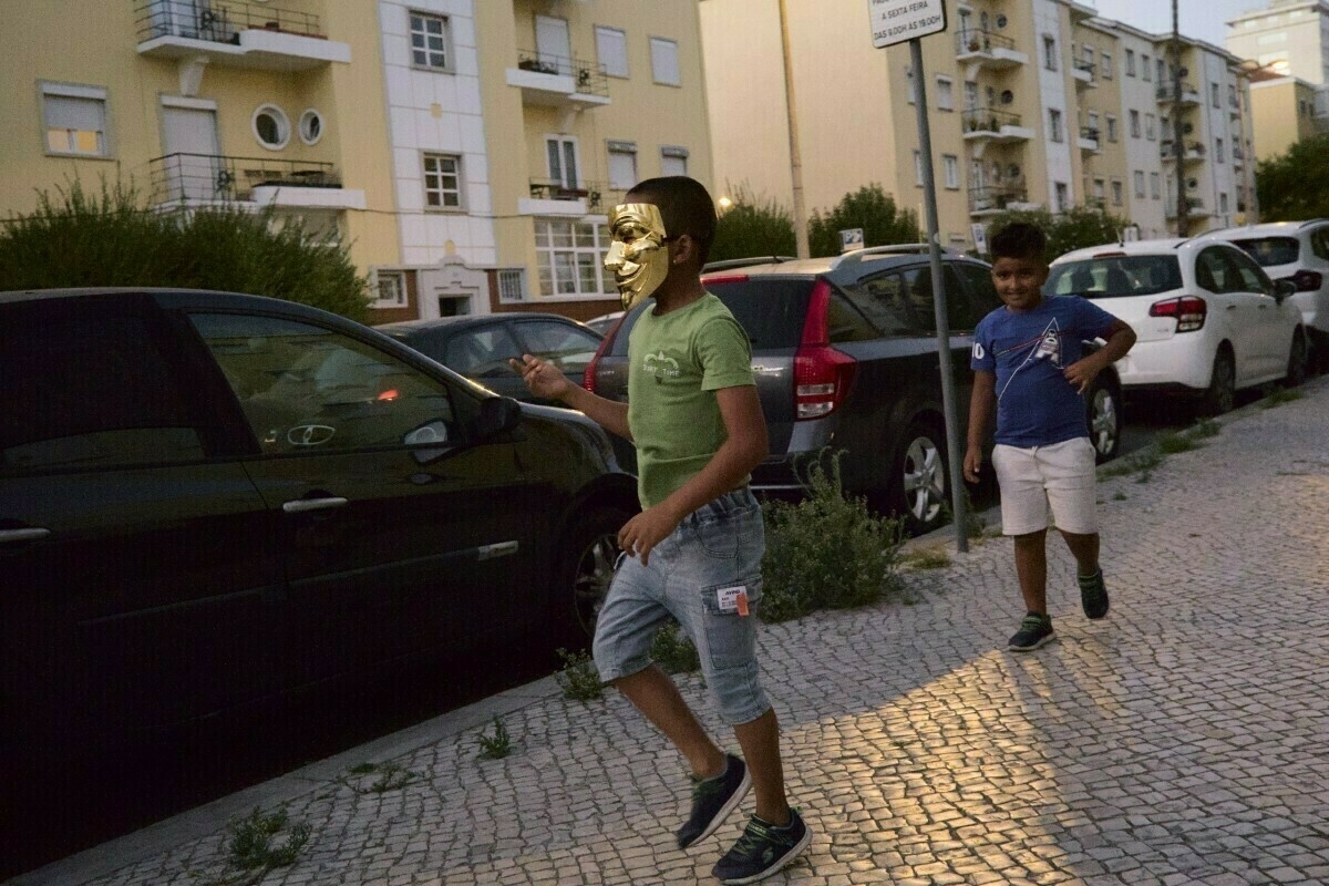 Boys running in street, one with golden mask